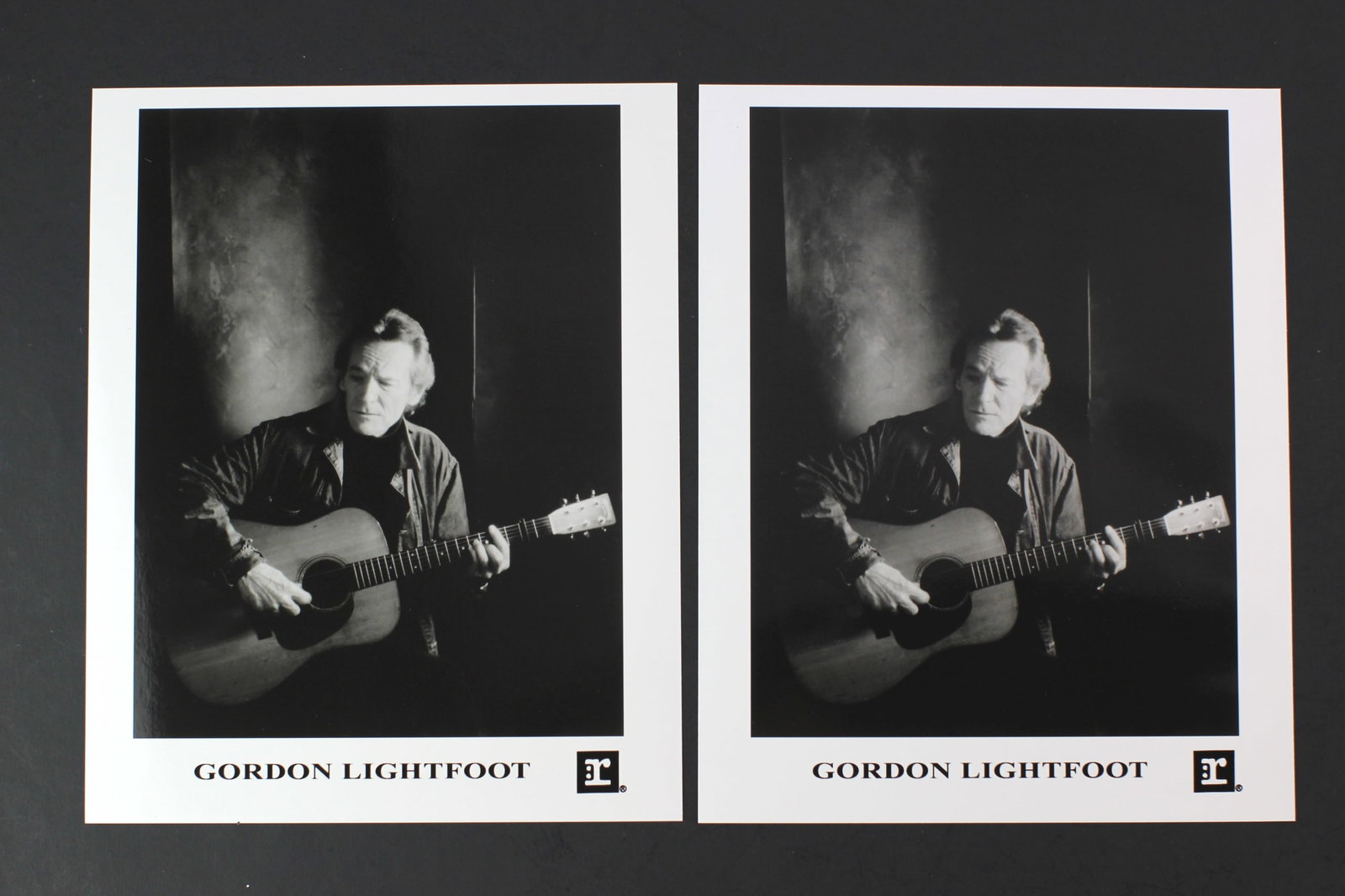 Gordon Lightfoot Promo Photos Pair: Pair of black-and-white promotional photos of Gordon Lightfoot, each showing him with guitar. Photos are approx. 8 in. (W) by 10 in. (H). Both prints remain in very good condition with only light