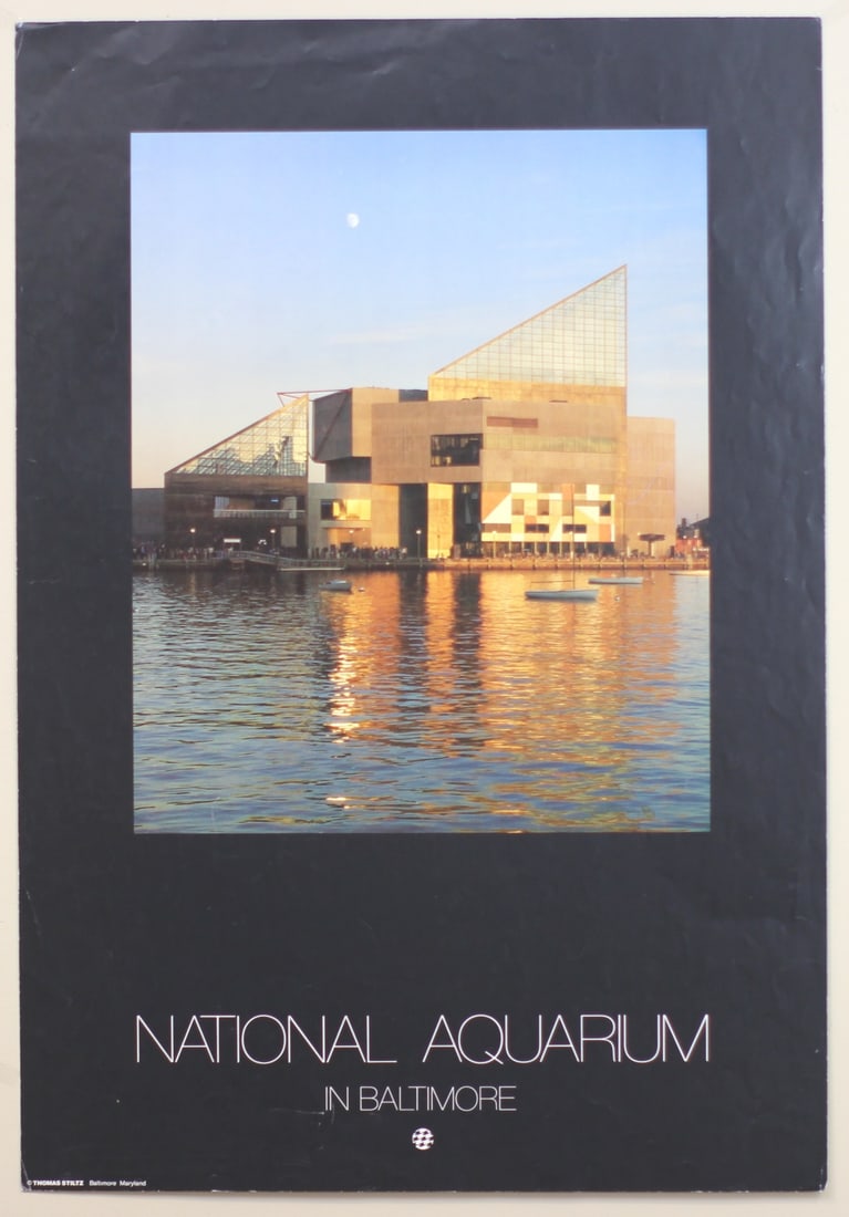 National Aquarium Baltimore Poster by Stiltz: Photographic poster of the National Aquarium in Baltimore, captured at sunset by Thomas Stiltz. Measures 32 inches in height by 22 inches in width. Features rich golden reflections on the harbor water