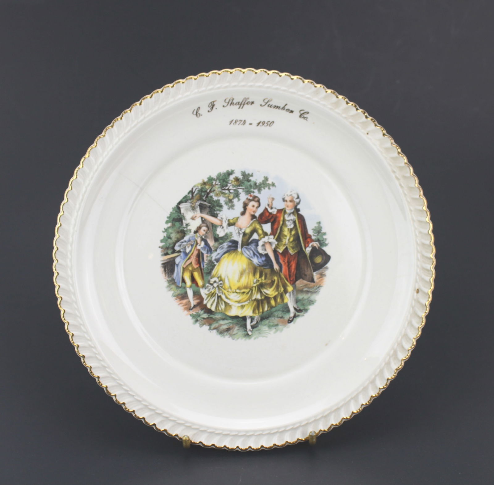 C. F. Shaffer Lumber Co. Anniversary Plate: Commemorative decorative plate by McArthur Pottery Co., marked for C.F. Shaffer Lumber Co. (1874–1950). Features a Rococo-style scene with gold trim, 22K gold stamp, and signs of age including crazi