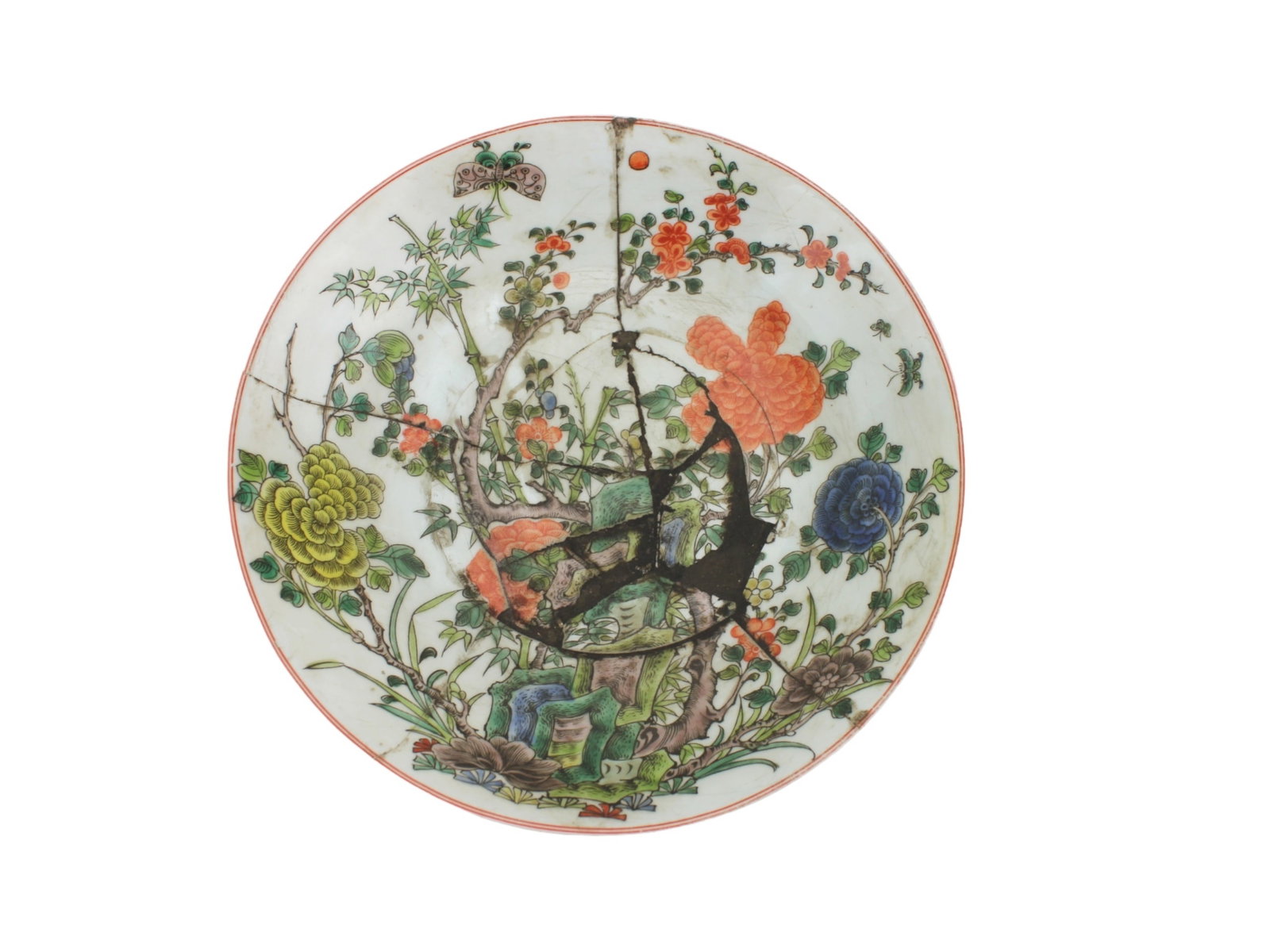 A Chinese Famille Rose Dish: A Chinese porcelain plate, decorated in famille rose enamels with flowers, butterflies, and foliage. The plate is heavily damaged and has been extensively restored, with visible cracks and old repair