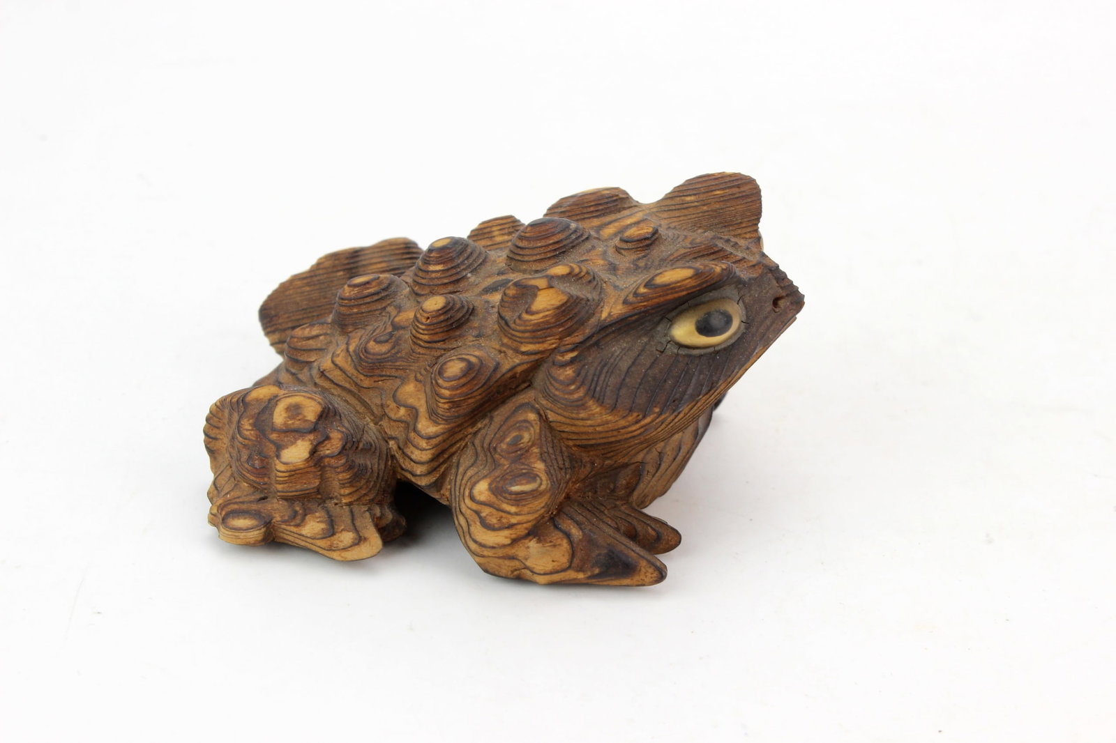 Carved Wood Frog Figurine: Carved wood frog figurine featuring pronounced textured bumps, layered wood-grain patterns, inset eyes, and a ?Japan? mark on the underside. Measures approximately 1 3/4 in. (H) ? 3 1/4 in. (L) ? 2