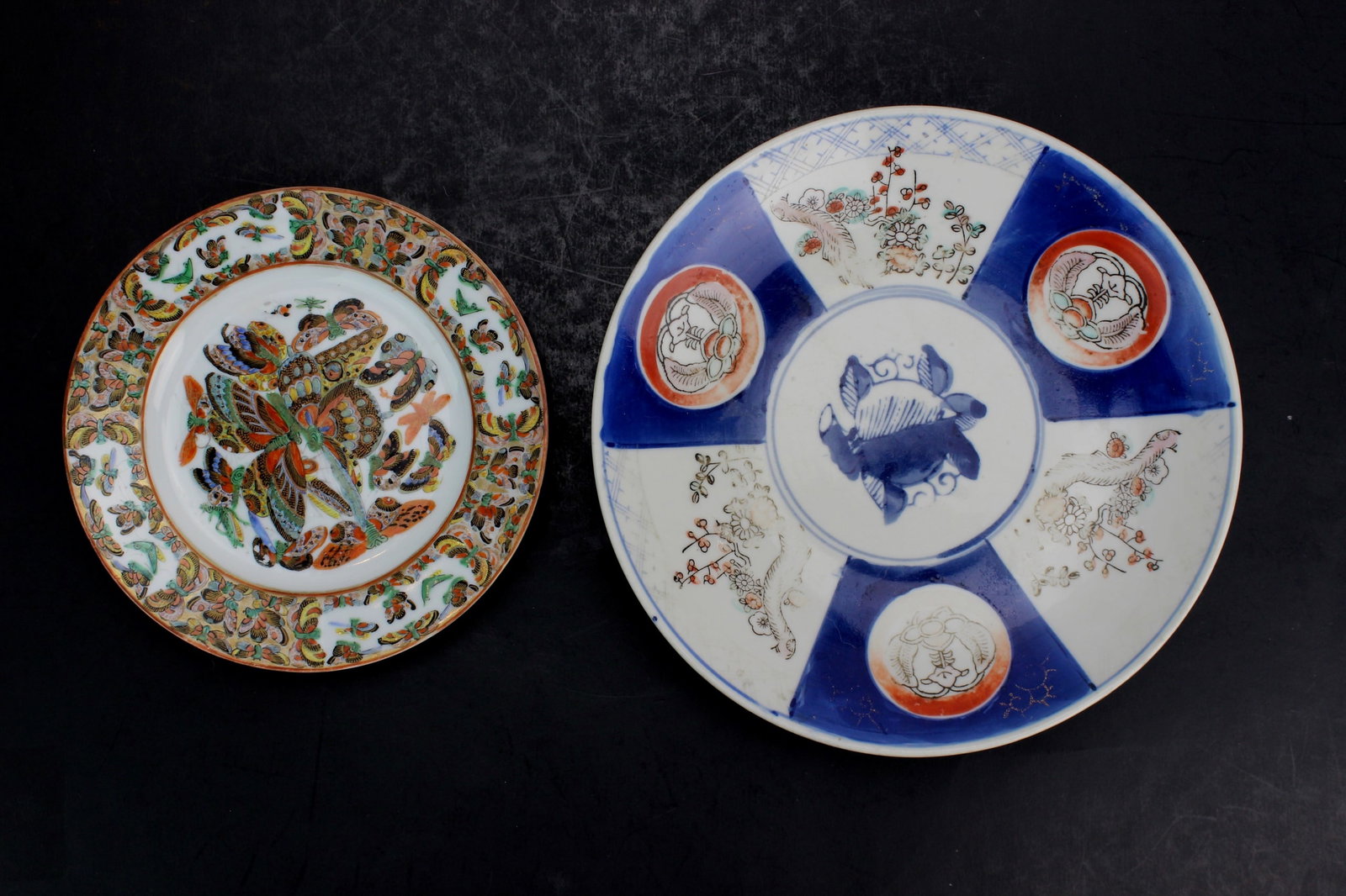 Two Decorated Porcelain Plates, Butterfly & Imari: Pair of vintage porcelain plates: one Imari-style with blue, red, and gold floral panels (9 1/4 in. D) and one Rose Medallion with butterflies and flowers (7 in. D). Both show light age wear, minor en