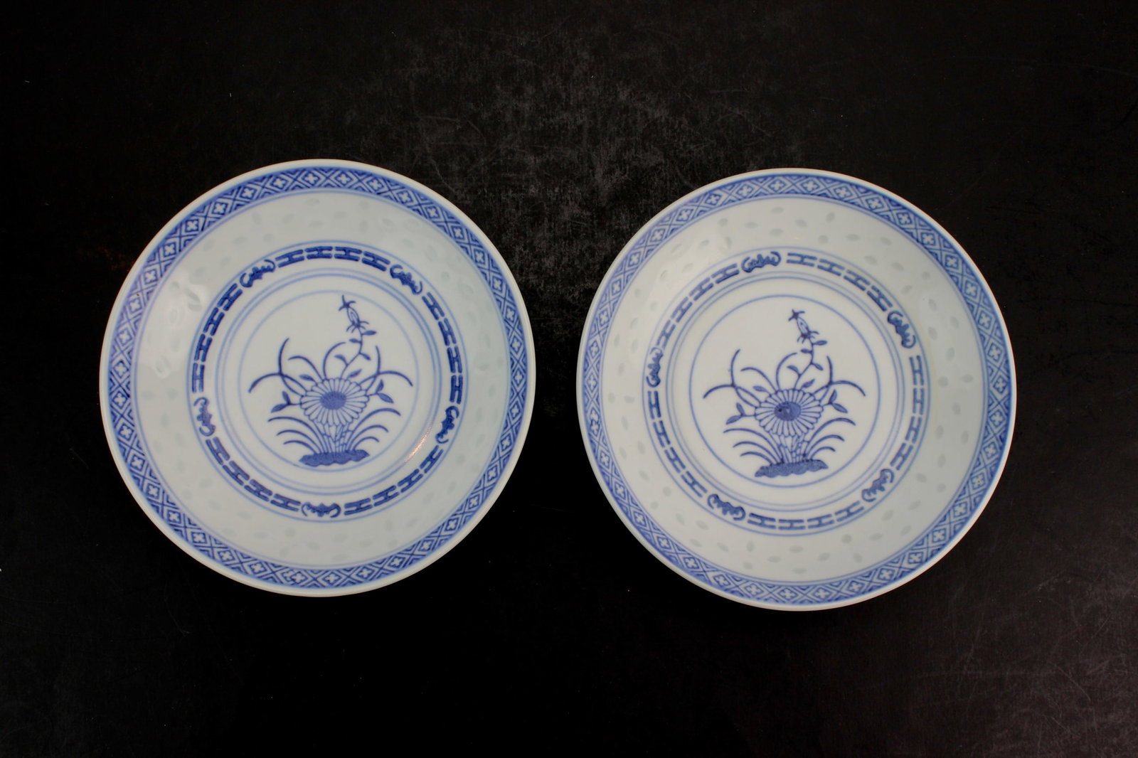 Pair of Chinese Blue & White Dishes: Pair of Chinese blue and white rice grain porcelain dishes with floral basket design, marked on base. In good condition. Each measures 5 1/2 in. (D).
