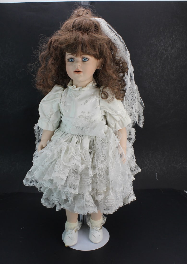 Val Shelton Signed Limited Edition Doll: Val Shelton signed limited edition porcelain doll with expressive blue eyes, curly brown hair, and layered lace dress with veil and accessories. numbered 3 of 25 limited edition. Size: 24 in. tall.
