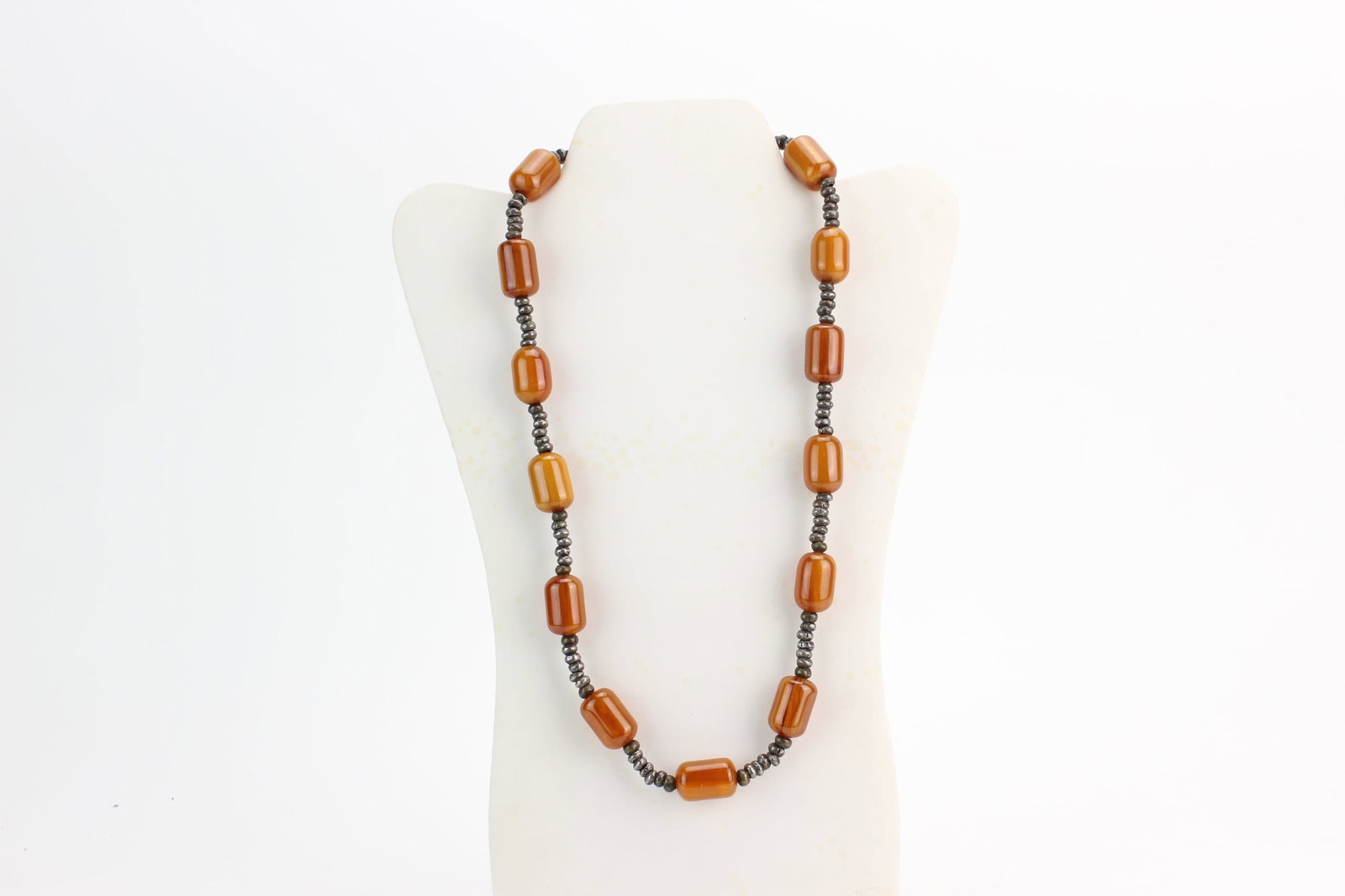Amber Style Bead Necklace w Spacers: Amber style necklace composed of cylindrical caramel-tone beads separated by silvertone spacer beads. Each bead measures approximately 22 mm in length; necklace measures 24 inches in length. Shows