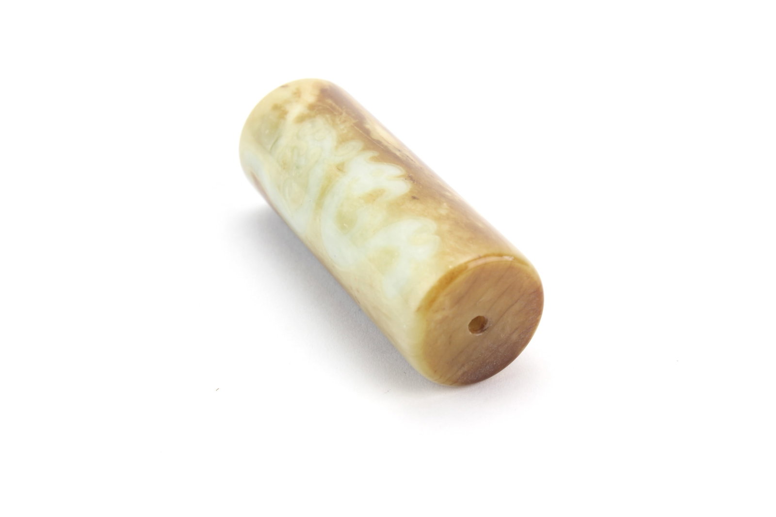 Chinese Cylindrical Jade Bead: Carved Chinese jade bead of cylindrical form with natural russet and celadon tone variations. Measures approximately 2 1/2 in. (L). Shows natural inclusions, surface wear, and minor imperfections