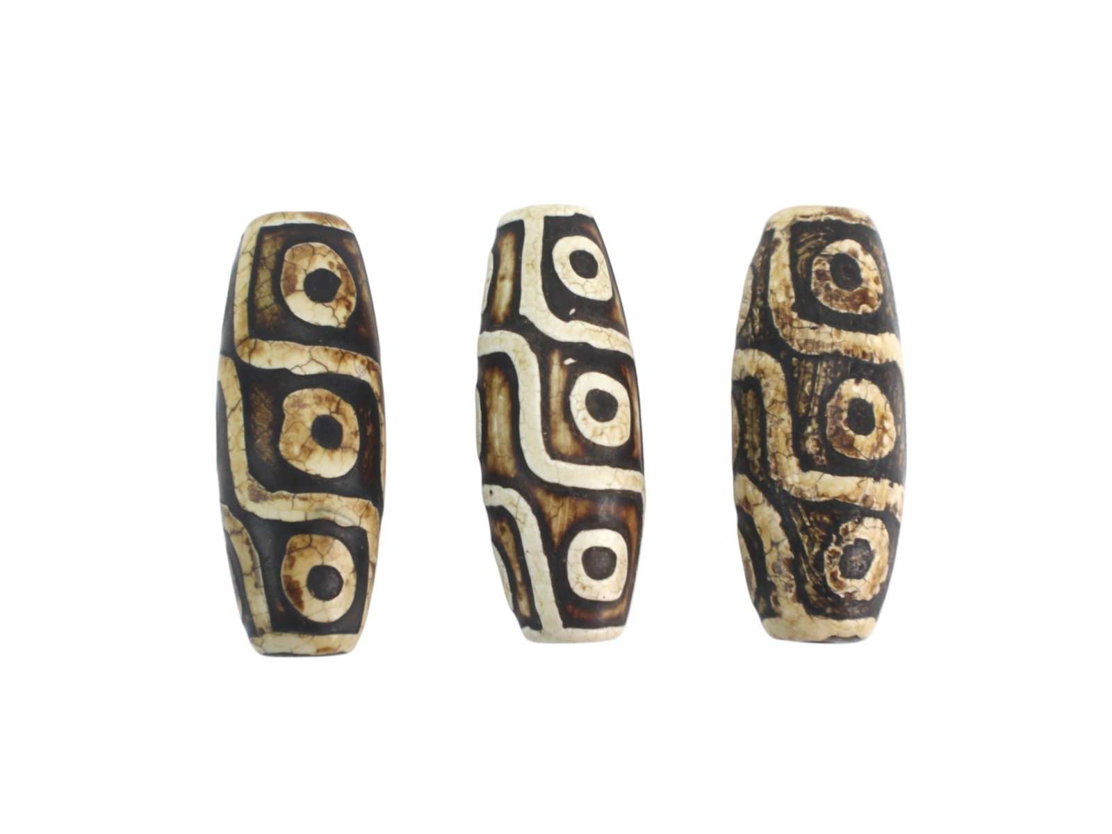 Set of Three Tibetan Nine-Eye Dzi Beads: Group of three cylindrical agate Dzi beads featuring the traditional ?Nine-Eye? motif with dark brown and cream patterns and zigzag borders. Drilled for stringing, likely 20th century with