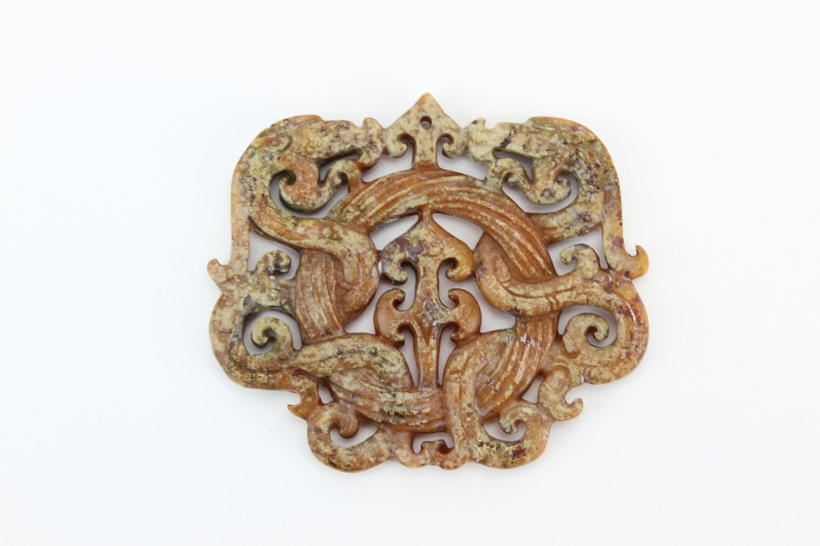 Chinese Archaic Style Jade Phoenix Plaque: Chinese archaic-style carved jade plaque of openwork form, decorated with confronting stylized phoenix motifs and scrolling elements. The stone displays mottled russet, beige, and brown coloration wit