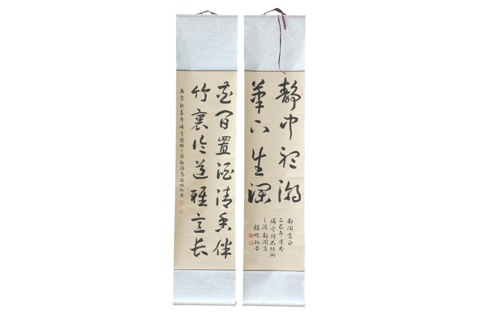 Pair of Chinese Calligraphy Hanging Scrolls: Pair of Chinese ink calligraphy hanging scrolls, each featuring bold vertical inscriptions with additional calligraphy and red seal marks, mounted on patterned silk brocade. Calligraphy measures 39 1/