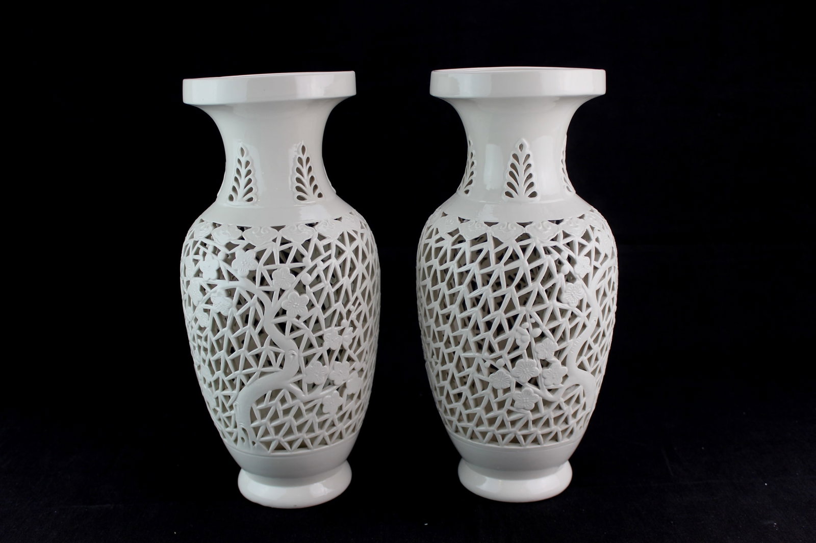 Pair White Reticulated Porcelain Vases: A matching pair of white porcelain vases featuring fine openwork reticulation with floral and branch motifs.. Each vase measures 12 3/4 in. tall. Drilled for lamps, with no visible chips or cracks.