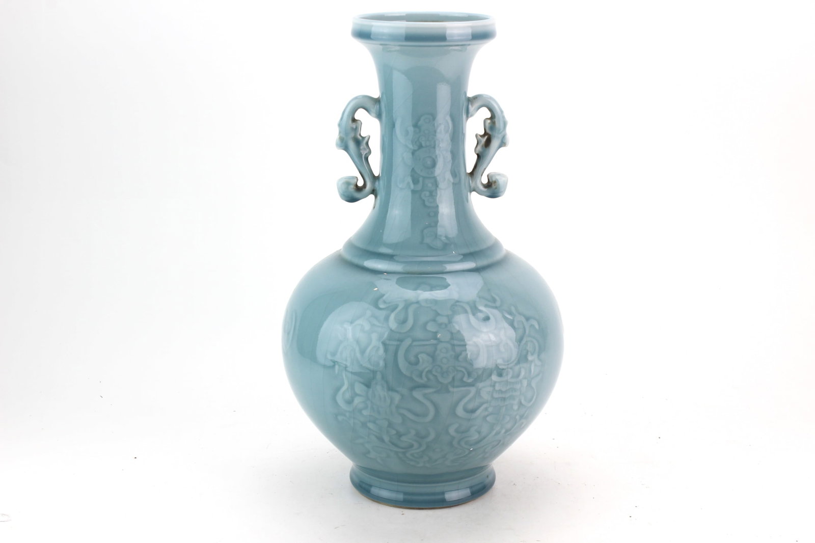 Chinese Celadon Glazed Double-Handle Vase: Chinese celadon-glazed porcelain vase of globular form with a tall neck, applied openwork handles, and subtle molded decoration featuring stylized motifs beneath the glaze. Measures 13 1/2 in. (H) X 8