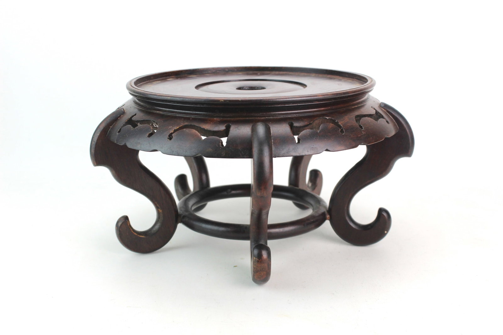 Chinese Carved Hardwood Display Stand: Chinese carved hardwood display stand with pierced apron and scrolling legs, finished in a dark patina. Likely used to display a vase, bowl, or sculpture. Measures approx. 11 in. (D) X 6 in.