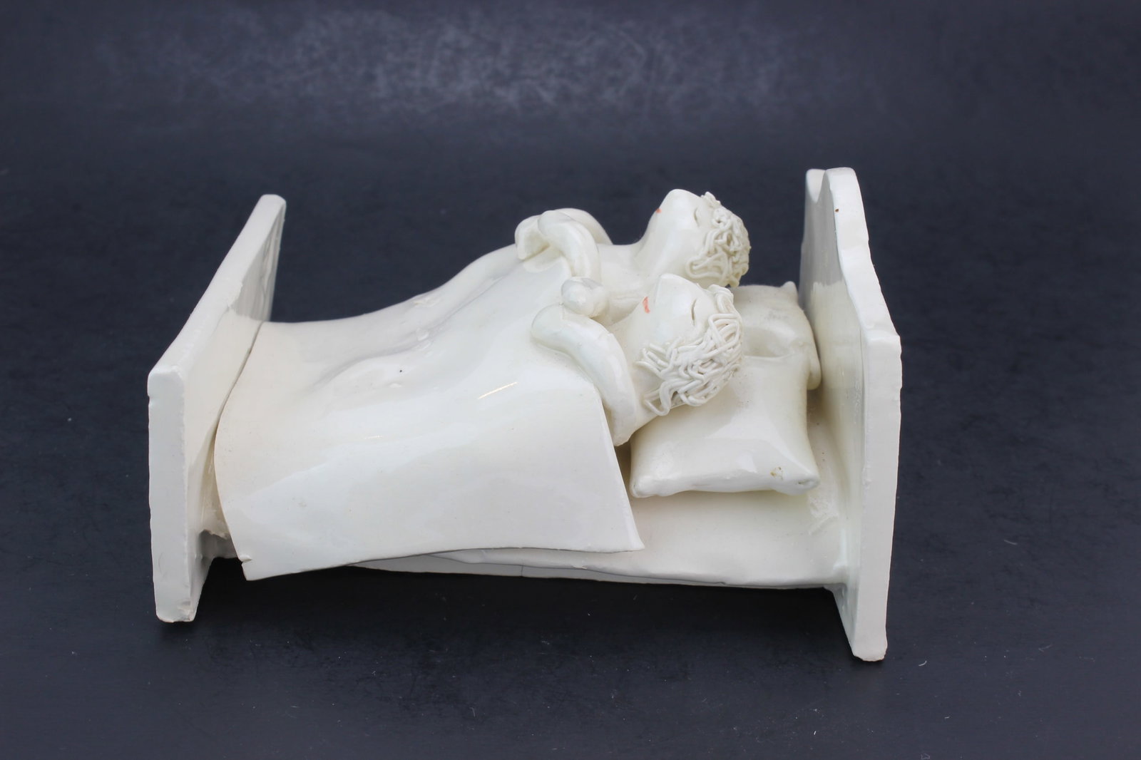 Solveig Cox White Pottery Figural Bed Sculpture: White porcelain figural sculpture depicting two children in a bed. Signed by Solveig Cox on the bottom. Measures approximately 6 in. (L) x 5 in. (W) x 3 1/2 in. (H). Overall good decorative condition 