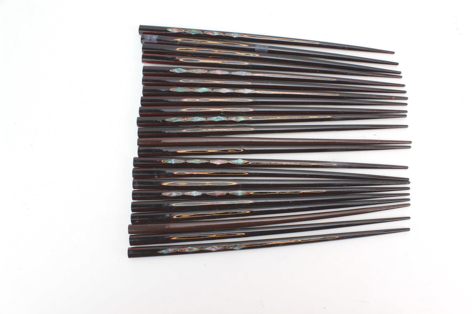 22 Inlaid Wooden Chopsticks Set: Lot of 22 dark wood chopsticks with decorative mother-of-pearl style inlay accents. Each measures approx. 9 in. (L). Showing light surface wear, minor scratches, and some finish loss consistent with
