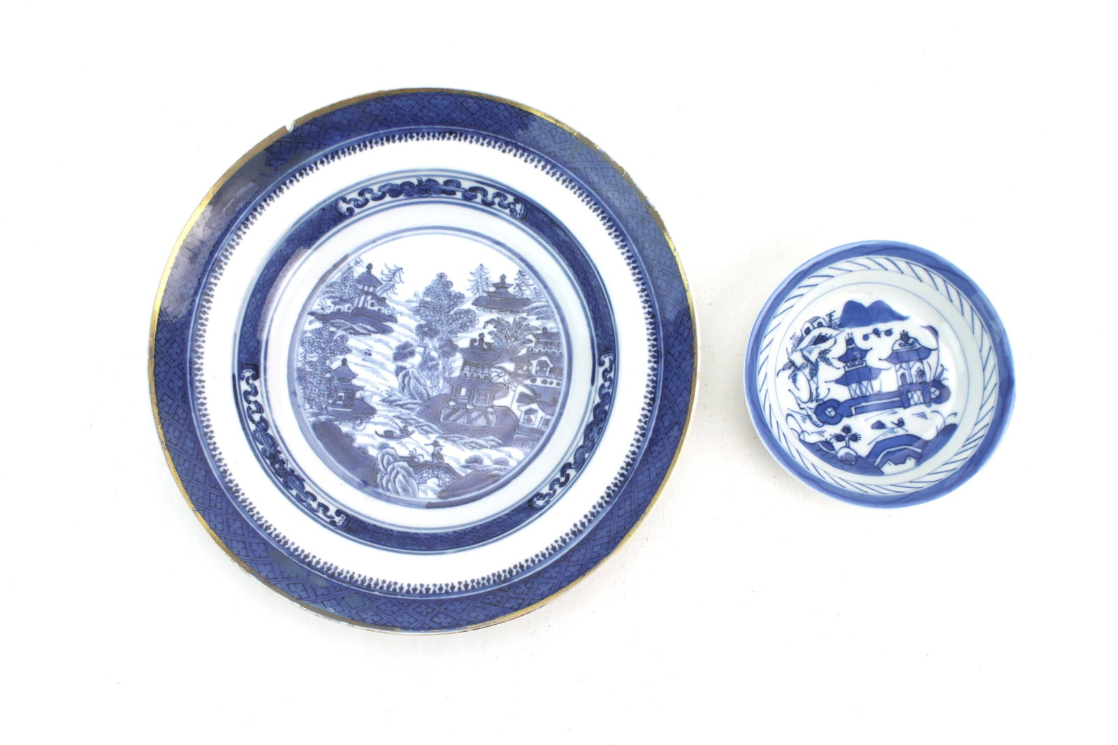 Two Chinese Export Blue & White Dishes: Two Chinese export blue-and-white pieces: a Nanking dish (10 in. ? 1 3/4 in.) with riverscape decoration, showing a rim chip, gilt wear, and a hairline; and a Canton saucer dish (5 in. ? 1 1/4 in.)