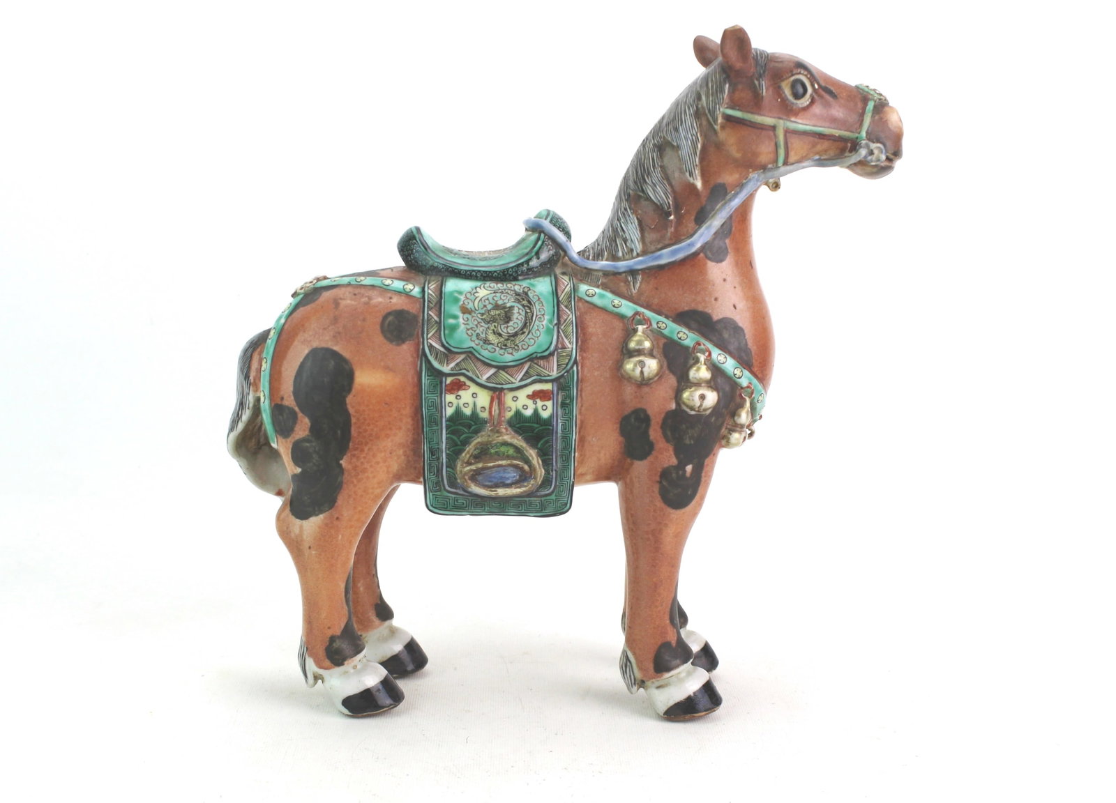 Chinese Famille Rose Porcelain Horse Figure: A finely brightly enameled Chinese porcelain horse, decorated with saddle and harness details. Measures 10 1/2 in. (H) ? 11 in. (L) ? 3 1/2 in. (W). Condition: ear tip chip, cracks around the neck