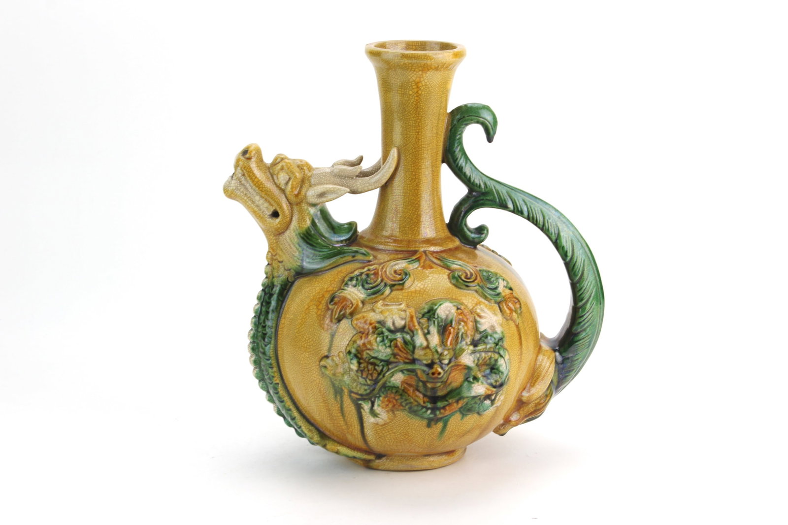 Chinese Sancai Glazed Dragon Ewer: Chinese ceramic ewer featuring sancai-style glaze in amber, green, and cream tones, modeled with a dragon-form spout and scrolling handle, the body decorated in relief with floral and foliate motifs a
