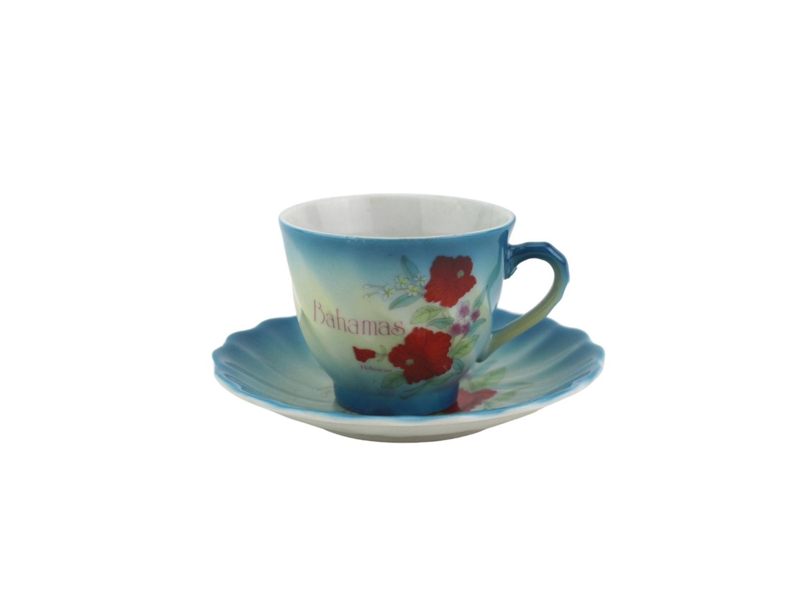 Bahamas Souvenir Teacup and Saucer Set: A decorative porcelain teacup and saucer set from the Bahamas, featuring red hibiscus flowers, a blue-to-cream gradient, and scalloped edges. Cup in 2 in. (H), Saucer in 4 1/2 in. (D). Provenance: