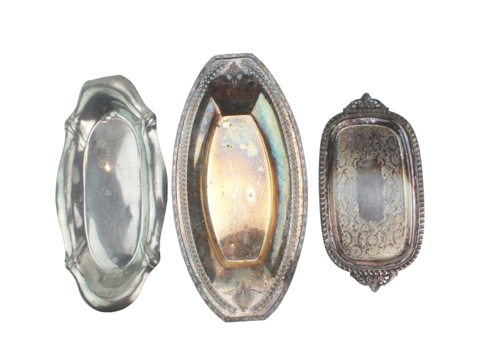 Three Vintage Oval Serving Trays: Set of three vintage silverplated serving trays?one Art Deco, one with pierced heart motifs marked ?E.P. Brass,? and one engraved ?1909? with scrollwork. All show patina and age wear. Largest
