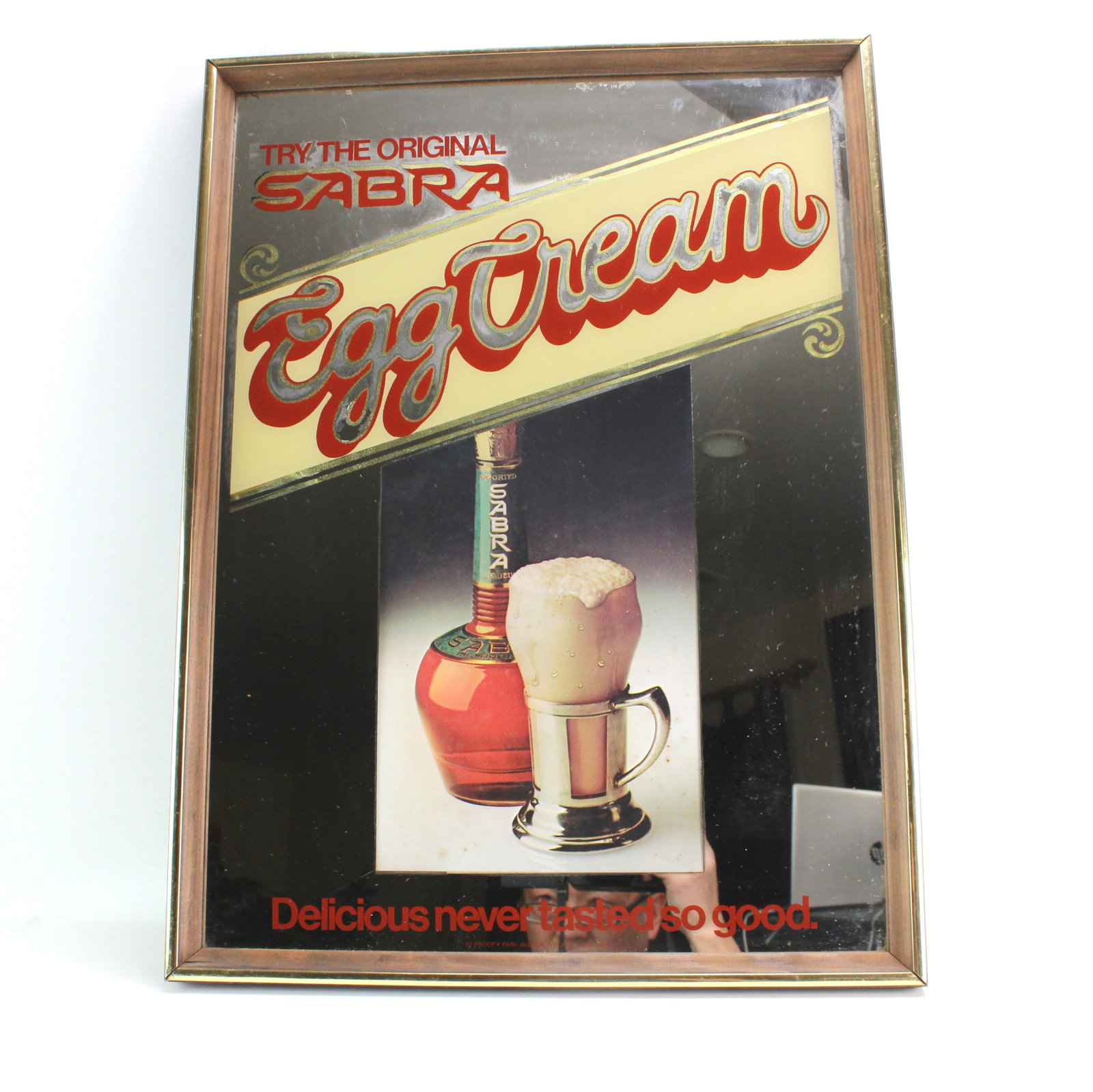 Sabra Egg Cream Advertising Wall Mirror Sign: Vintage mirror sign for Sabra Egg Cream liqueur featuring colorful graphics, promotional slogans, and a brass-toned frame. Dimensions: 23 in. (L) X 17 in. (W).