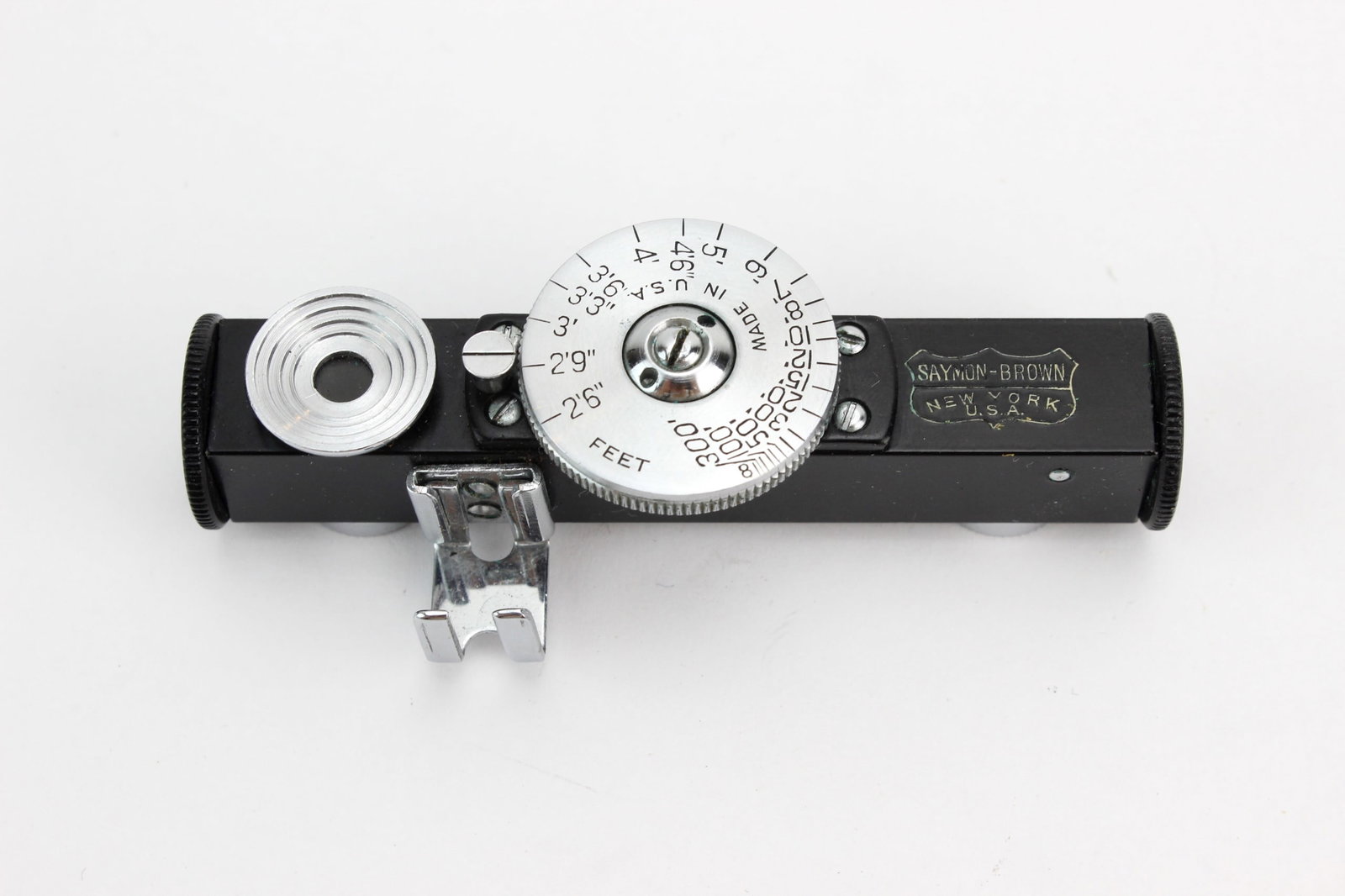 Saymon-Brown Accessory Rangefinder: Vintage Saymon-Brown accessory rangefinder in black and chrome finish, marked ?Saymon-Brown, New York, U.S.A.? Features a rotating distance scale calibrated in feet and an accessory mounting bracket.
