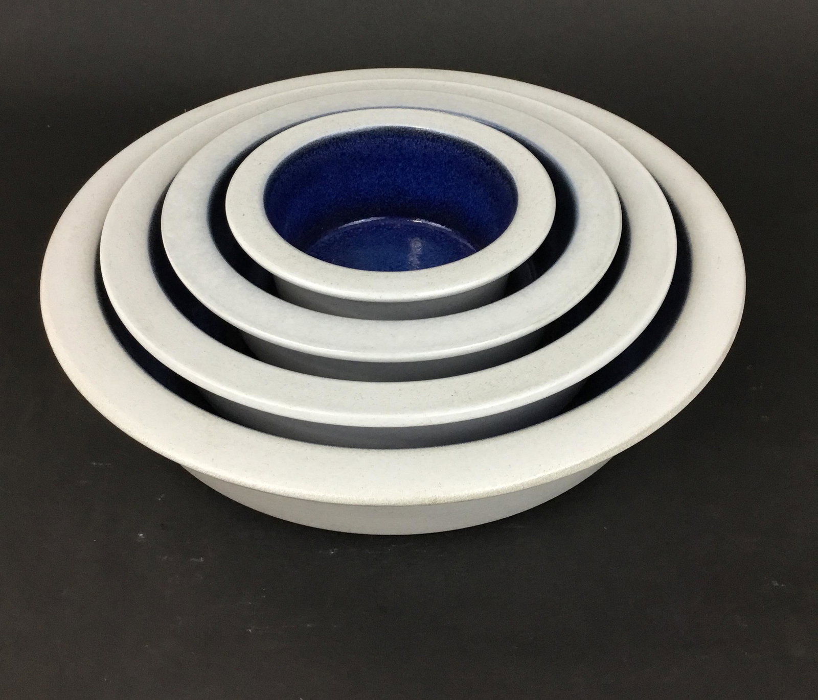 Set of Four Pottery Nesting Heath Bowls: Gorgeous set of nesting flat-bottomed ceramic dishes by Edith Heath Ceramics. Cream and dark blue. Largest is 11.5" across and 3" high.