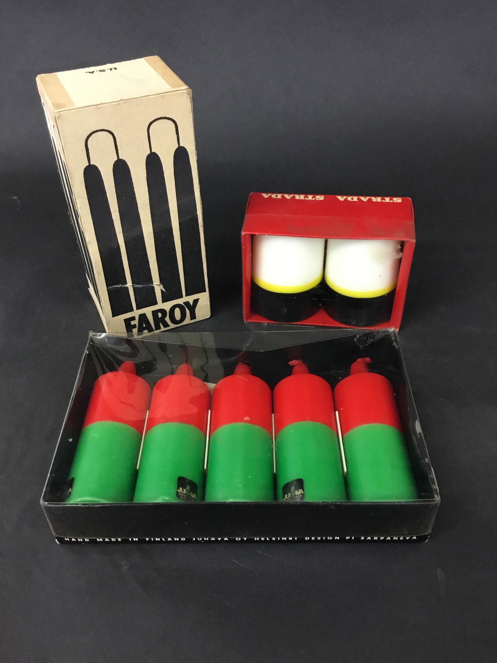Vintage Candles Finland Sarpaneva Juhava: 3 boxes of vintage candles. Faroy - a partial box of green tapers 6.75" long; 2 boxes of Juhava Oy Helsinki designed by Timo Sarpaneva. The red/green are 4.5" tall and the Strada pair are 3" tall. Sup