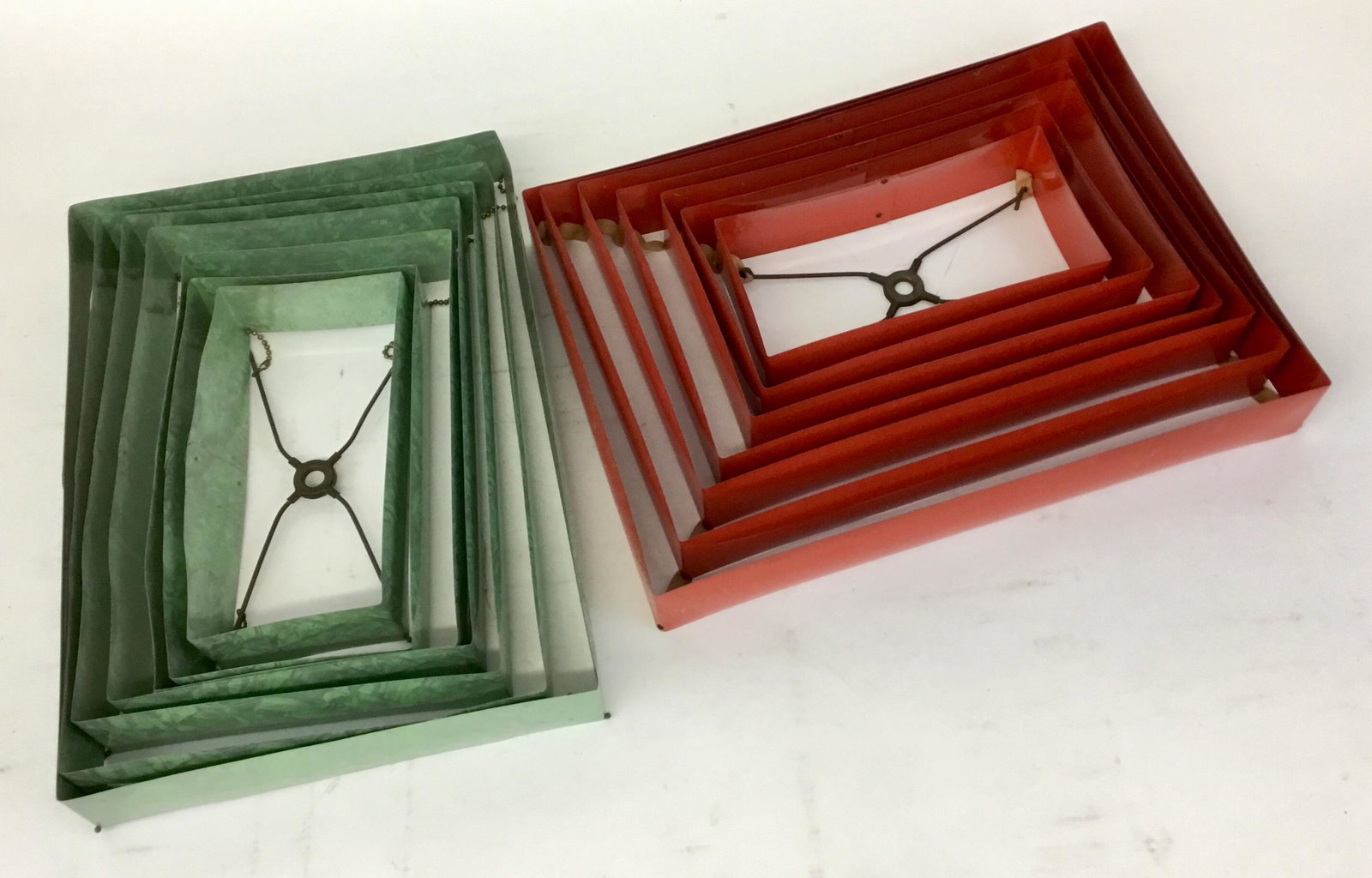 Lot of Two 1950s Metal Pagoda Lamp Shades: 2 great old mid-century metal stepped collapsible pagoda lampshades, one in silver and mint green and one in cherry red. The red one has cloth holding the levels together and the silver has ball chain