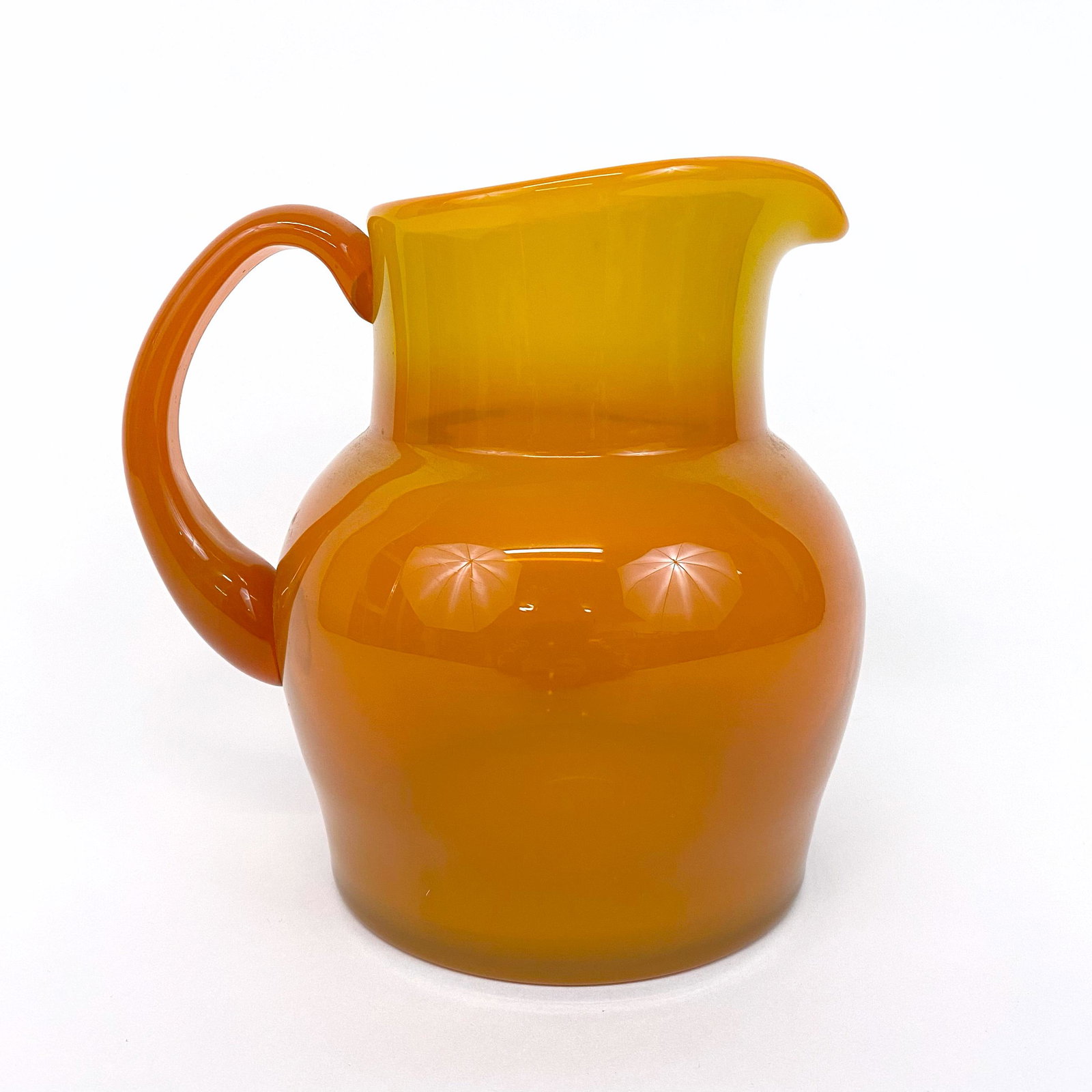 Erik Hoglund Swedish Art Glass Pitcher for Boda: Glowing orange glass pitcher by Erik Hoglund for Boda. Signed on base. 7.25" tall and 7" from spout to handle.