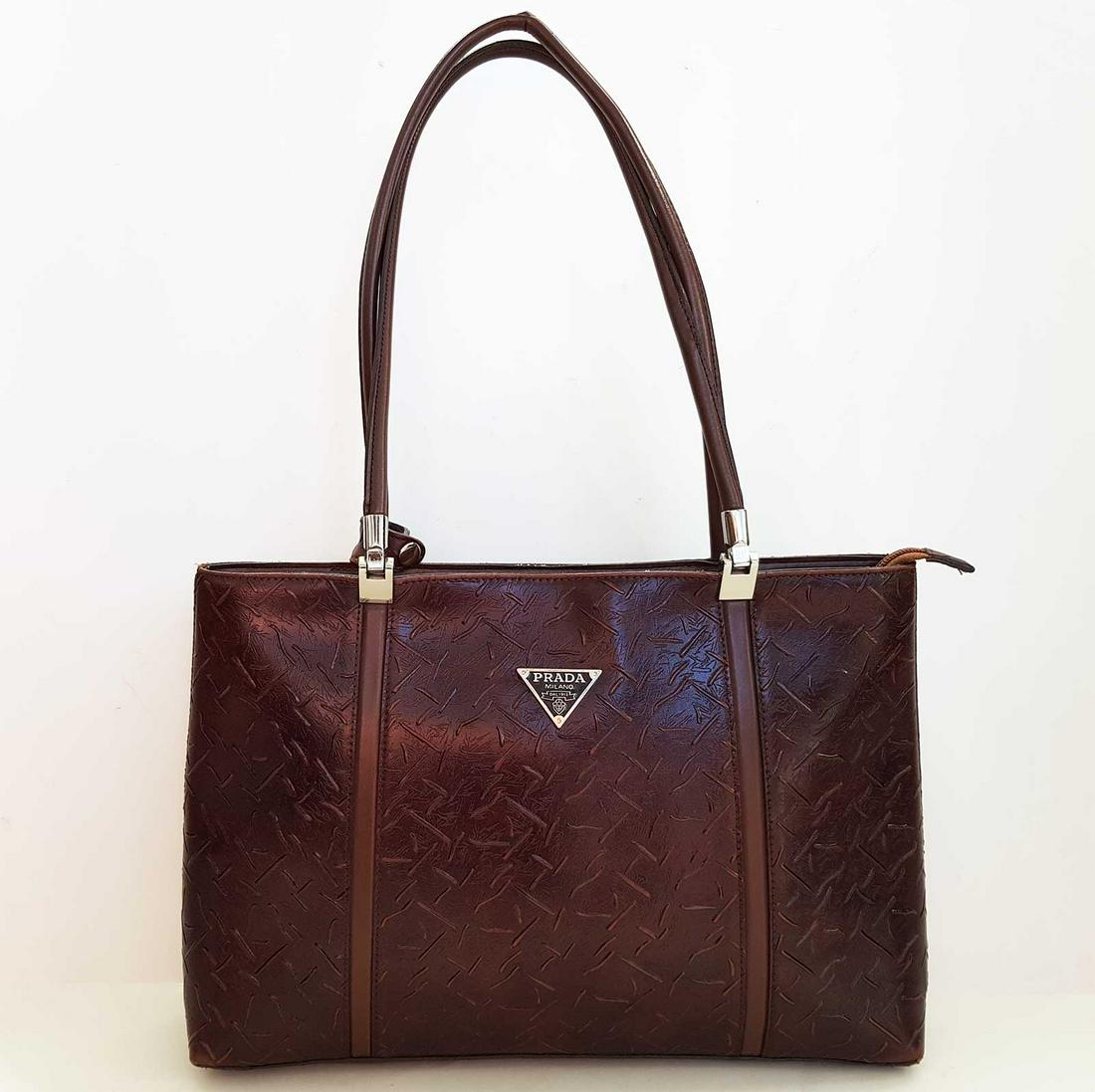 HANDBAG CALFSKIN with LOGO PRADA: EMBOSSED CALFSKIN SATCHEL with LOGO PRADA. This stylish bag is embossed calfskin leather in deep brown. The bag features leather top handles, a signature triangle logo. The top is open to a interior w