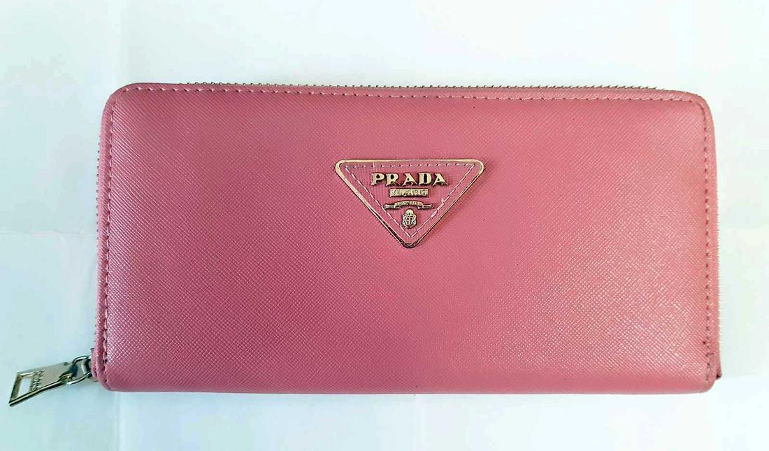 PRADA SAFFIANO LEATHER ZIP AROUND WALLET PINK: PRADA SAFFIANO WOMEN'S LEATHER LONG BILL WALLET. This pink Prada wallet opens with an elegant brass gold-plated Prada. There are eight convenient easy-to-access card holder slots revealed upon openin