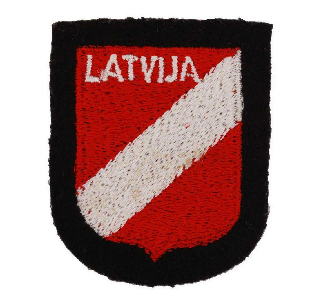GERMAN WW2 WAFFEN SS LATVIAN SLEEVE SHIELD: GERMAN WW2 WAFFEN SS LATVIAN SLEEVE SHIELD A German WWII Waffen SS Latvian volunteer sleeve shield insignia made of red and white machine embroidery, with Latvija embroidered in white uppercase letter