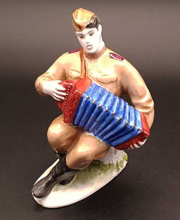 RUSSIAN PORCELAIN FIGURINE, VASILIY TYORKIN: RUSSIAN SOVIET PORCELAIN FIGURINE, VASILIY TYORKIN, c.1950 A Russian hand-painted porcelain figurine of Vasili Tyorkin, a Soviet soldier sitting on a stump and playing the harmonica. The original mode