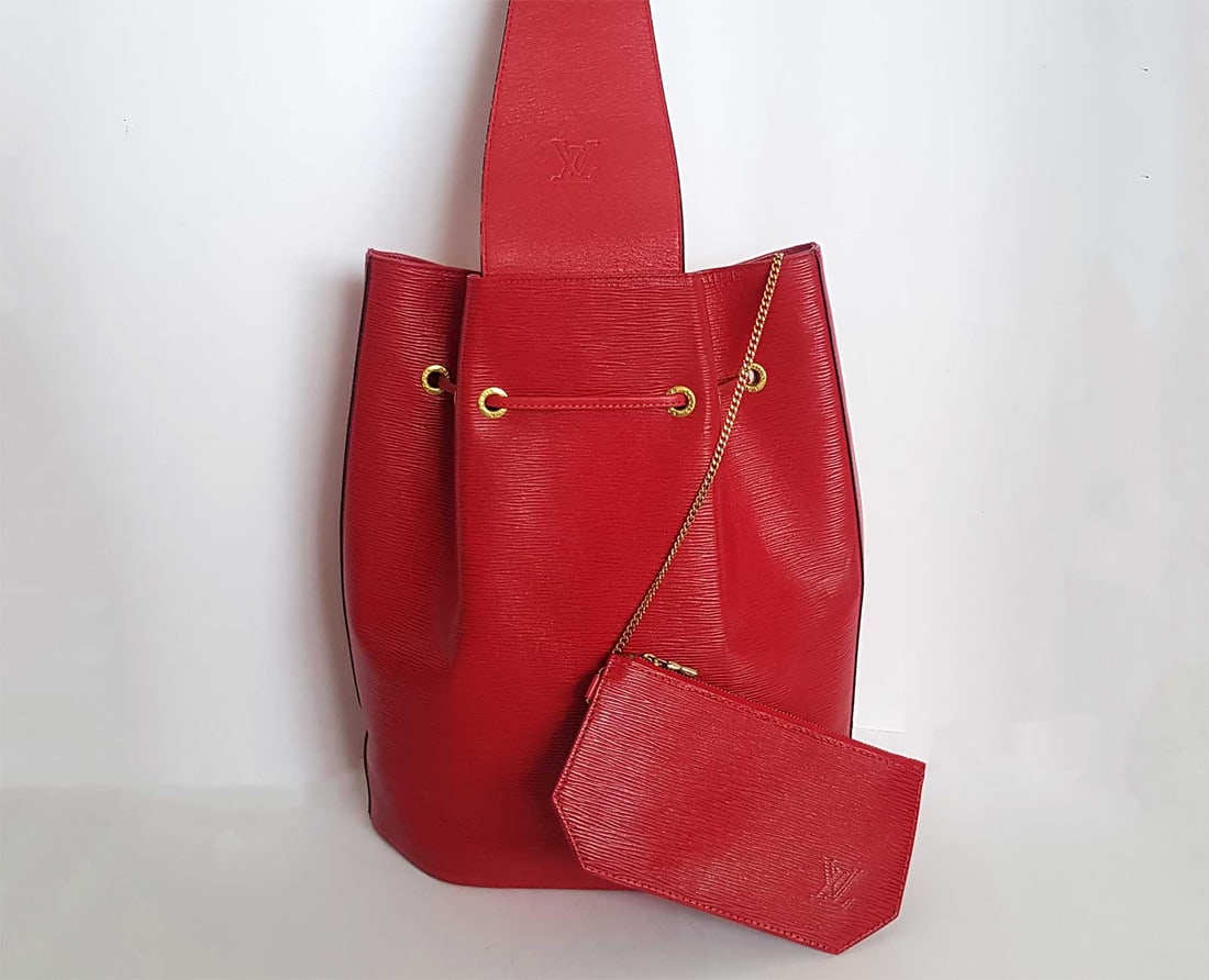 LOUIS VUITTON VINTAGE BUCKET BAG: LOUIS VUITTON NOE BUCKET & DRAWSTRING BAG RED LEATHER EPI This beautiful vintage Louis Vuitton Noe Bucket Bag is crafted from red Epi leather, subtly embossed with the Louis Vuitton initials. It featu