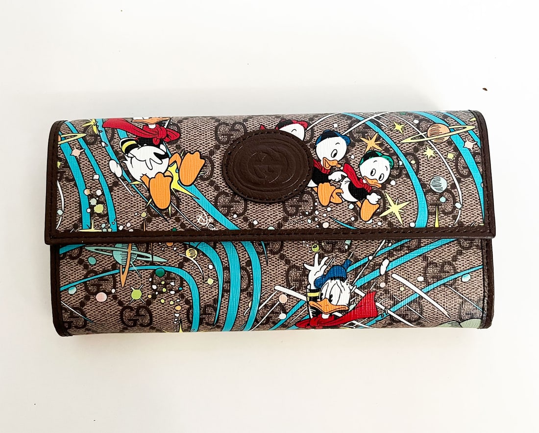 GUCCI LIMITED EDITION CONTINENTAL WALLET: GUCCI x DISNEY BEIGE GG SUPREME DONALD DUCK CONTINENTAL WALLET This is GUCCI X DISNEY GG Supreme Monogram Donald Duck Continental Wallet in Beige, Multicolor, and New Acero. This stylish long wallet