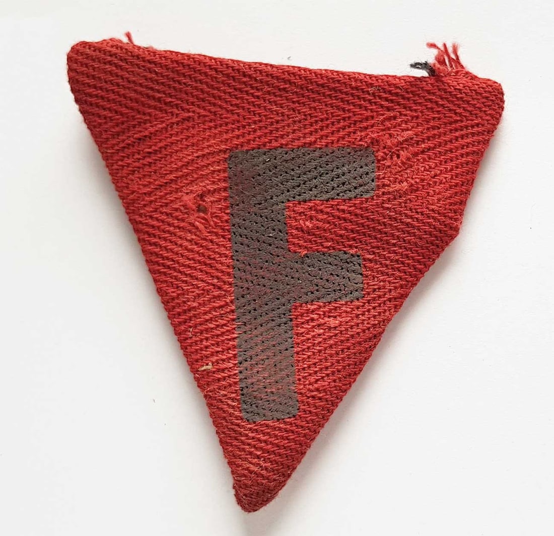 GERMAN WWII PRISONERS TAG fr. BUCHENWALD: Display Item! Price Reduced — Limited-Time Offer! GERMAN WWII PRISONERS TAG from BUCHENWALD CONCENTRATION CAMP This artifact is a red inverted triangle badge featuring the letter "F", signifying a p