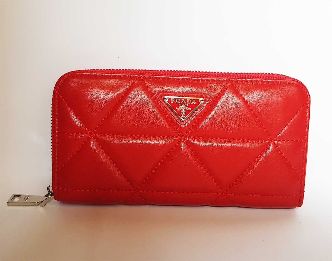 PRADA RED LEATHER ZIPPY WALLET: PRADA RED LEATHER ZIPPY AROUND LONG WALLET This nice wallet from Prada is one creation for a every fashionista. The gold-tone top zipper opens to reveal a leather-fabric lined interior featuring multi