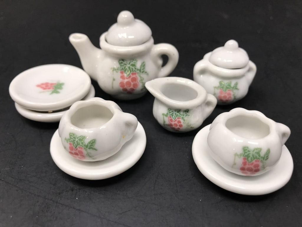 Miniature Tea Set Pink Grape Motif: Miniature Tea Set Pink Grape Motif. Tea pot with lid, sugar with lid, creamer, 2 tea cups and saucers, 2 plates. 11 pieces total. 1.75"h x 4"w x 2.5"d. 8 oz.