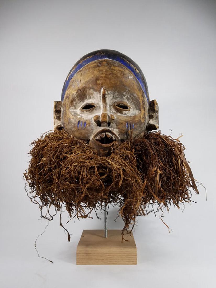 Yoruba Helmet Mask with Raffia: African Art: Visually striking Yoruba helmet mask with ritual scarification on cheeks. Sharp teeth and a powerful look. Signs of age and use.10.5"x11"
