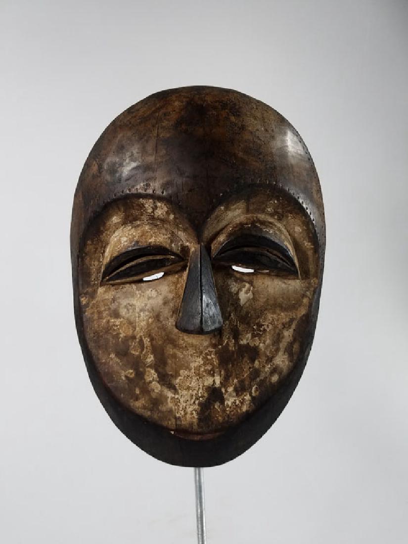Gabon Kwele Mask: African Art; Round with encrusted white pigment, scarification in the form of dots around edges. Nice reddish patina, old heavy piece.10x9.5x7"