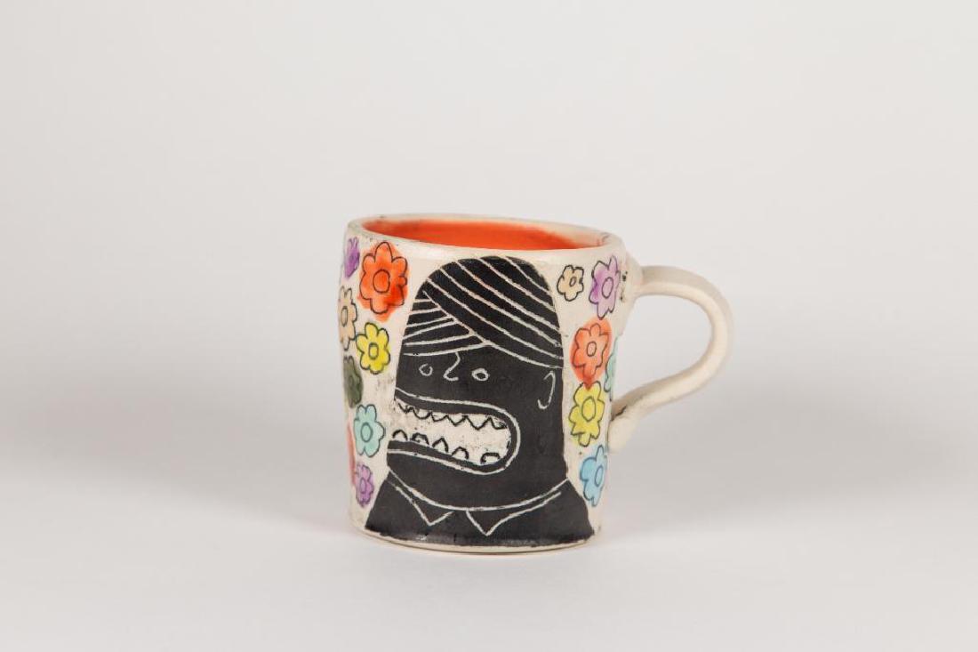 Kurt Anderson (American) Monster Cup: Kurt Anderson (American) wheel thrown, hand decorated cup with black figures drawn on either side. Incised line in the shape of flowers are painted with orange, red, and purple glaze. Cup is dipped in