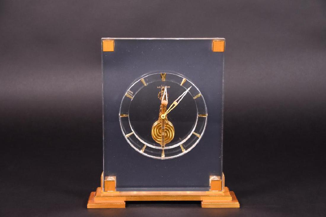 Jaeger LeCoultre Lucite Clock: Jaeger LeCoultre lucite desk or mantel clock composed of vertical rectangular lucite body or case with brass accented corners with circular minimal and modern clock face with tapered hour dashes with 