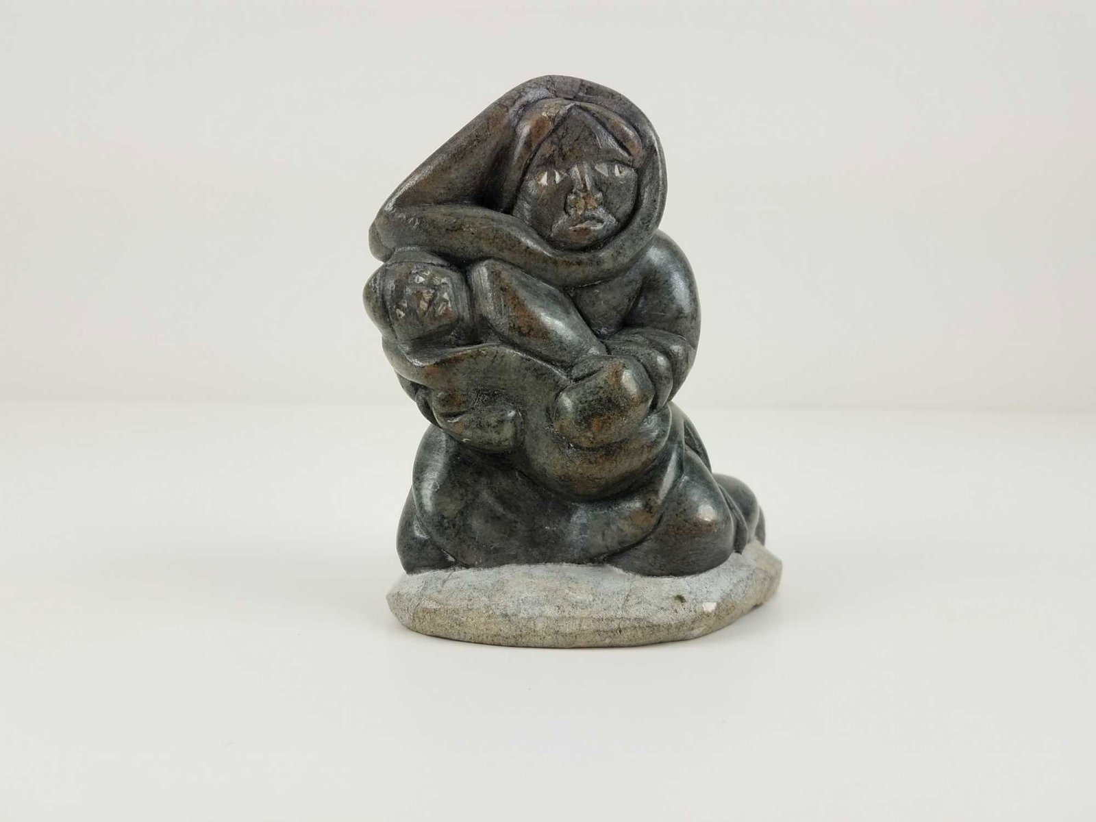 Inuit Mother and Child Soapstone Sculpture: Inuit soapstone sculpture of a mother and a baby. It is signed on the bottom, but a Canada Eskimo Art stick is obstructing it. MEASUREMENTS: 4.5" x 3" x 2.5" CONDITION: good.