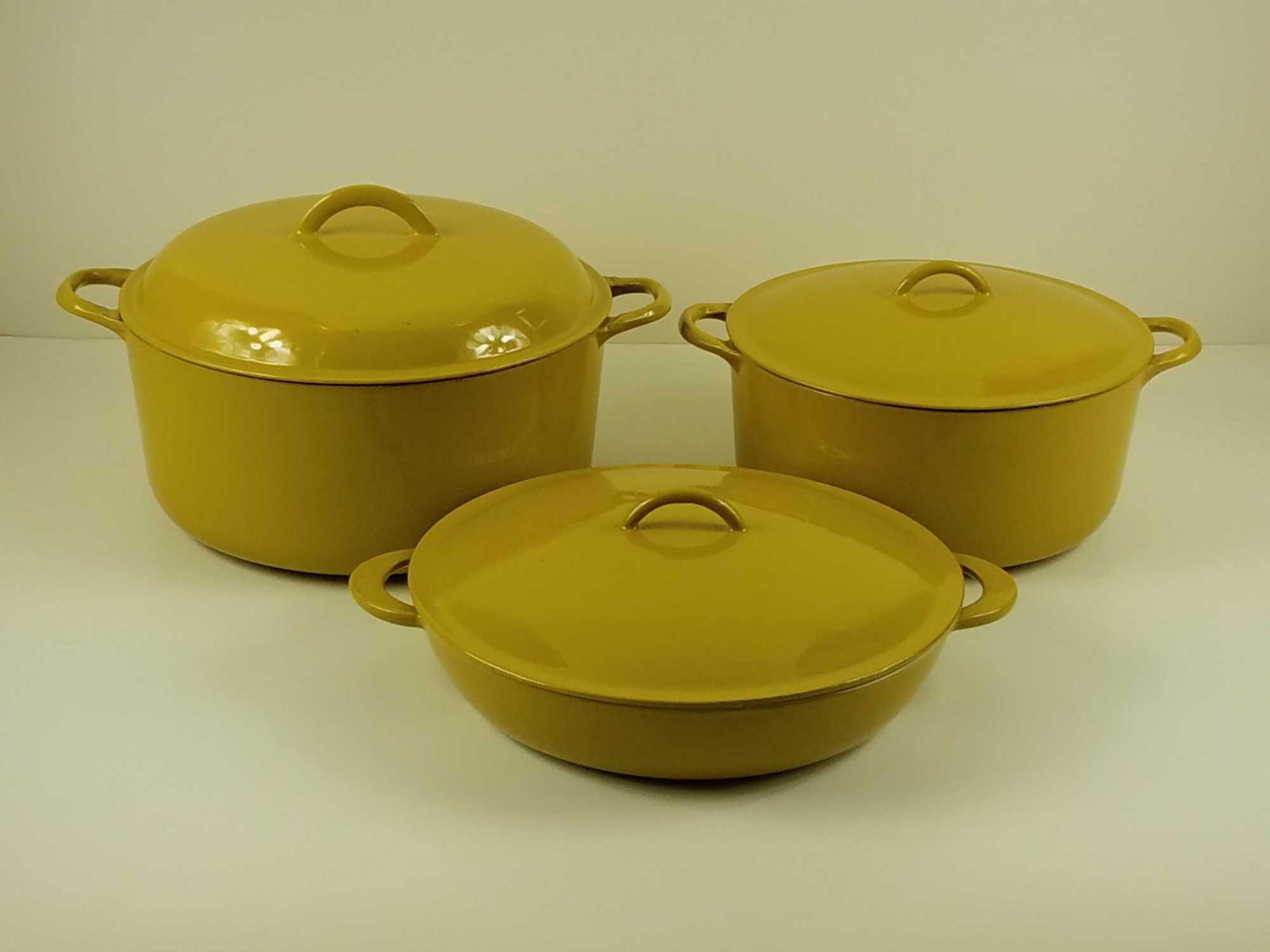 Descoware Cast Iron Skillet Set in Mustard Yellow (3): Lot of three (3) mustard yellow Descoware cast iron cookware. Includes: One (1) 3 qt dutch oven with lid, model number 2F 12 MEASUREMENTS: 12" in diameter. 5" deep. One (1) is a 10 qt dutch oven with 