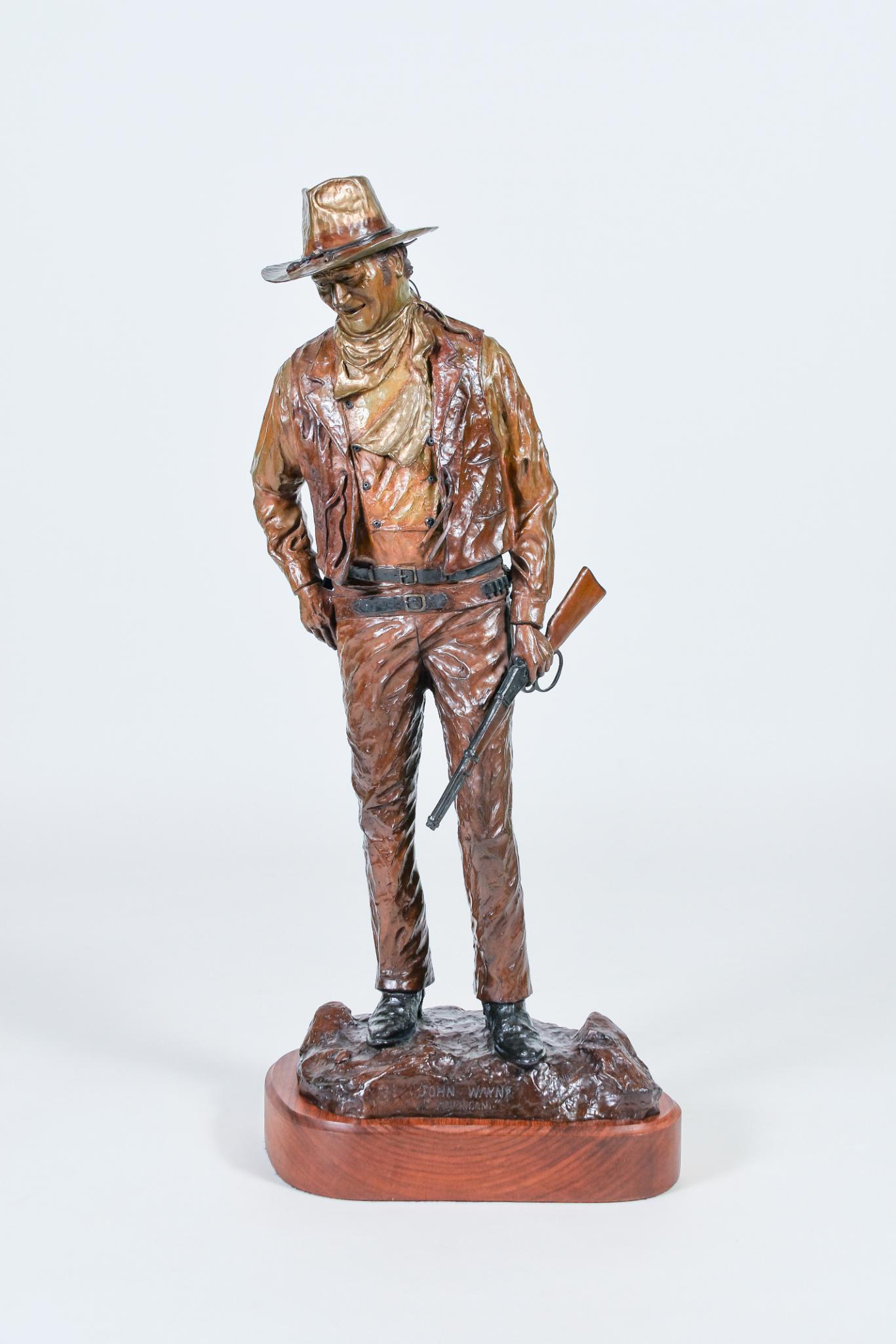 Dave Manuel's John Wayne Bronze Sculpture: Dave Manuel's John Wayne Bronze Sculpture with Winchester rifle and cowboy outfit. H30.5" on a wooden base, copyright 1979, numbered 224/250. Entitled on plinth, "John Wayne, American", also signed Bi