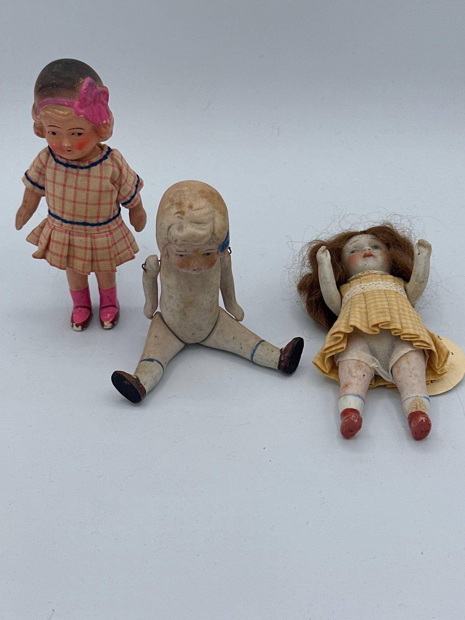 (3) Bisque Dolls: (3) bisque dolls: 5"all bisque Nippon wire strung girl with yellow dress 5" made in Japan All bisque girl with wire strung limbs 5" made in Japan painted bisque girl with pink bow
