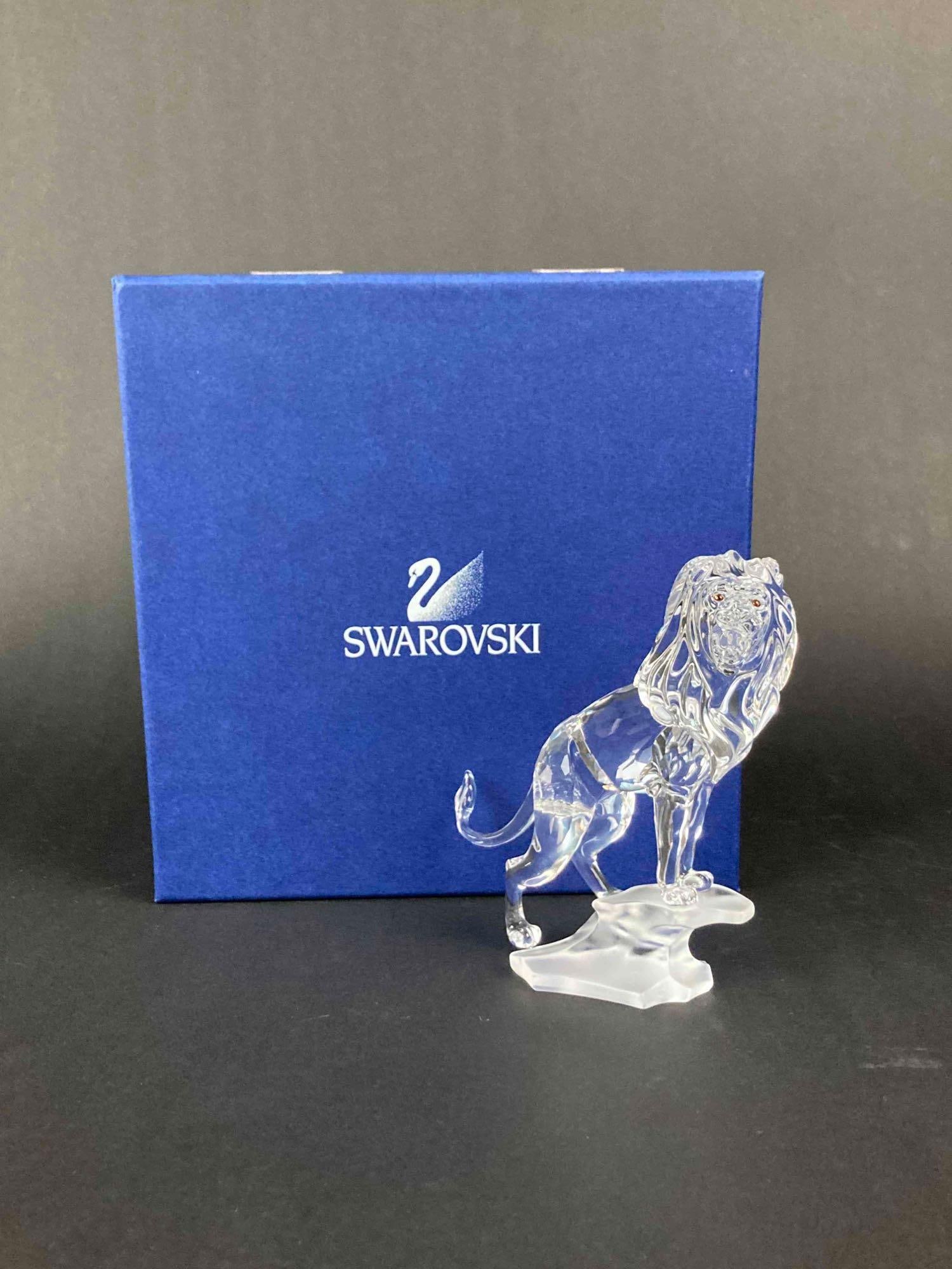 Swarovski Lion Figurine in Original Fitted Box: Swarovski Lion Figurine in Original Fitted Box. Crystal lion standing on a frosted crystal rock. Lion bears Swarovski trademark on the base. Deep brown crystal eyes. Figurine is in excellent condition