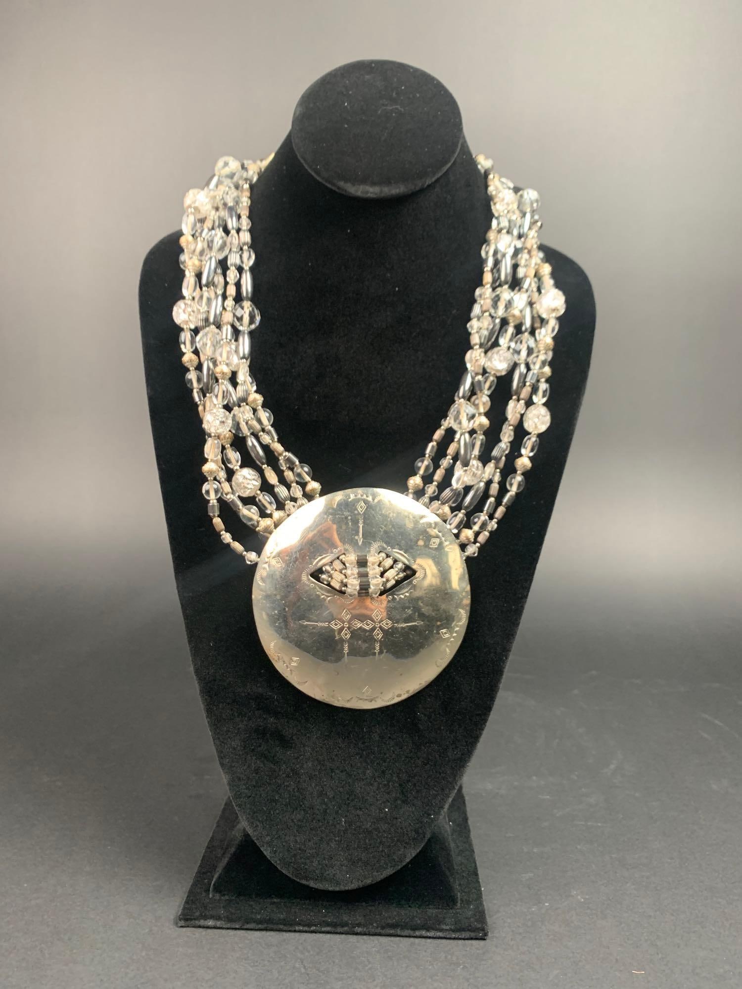 David Navarro Large Disc Multi-Strand Necklace (1970's): Necklace by jewelry designer David Navarro. Made of multiple strands of silver colored, clear, and gray metallic beads with a large silver patinated disc. Signed " Navarro" on the back of the 
