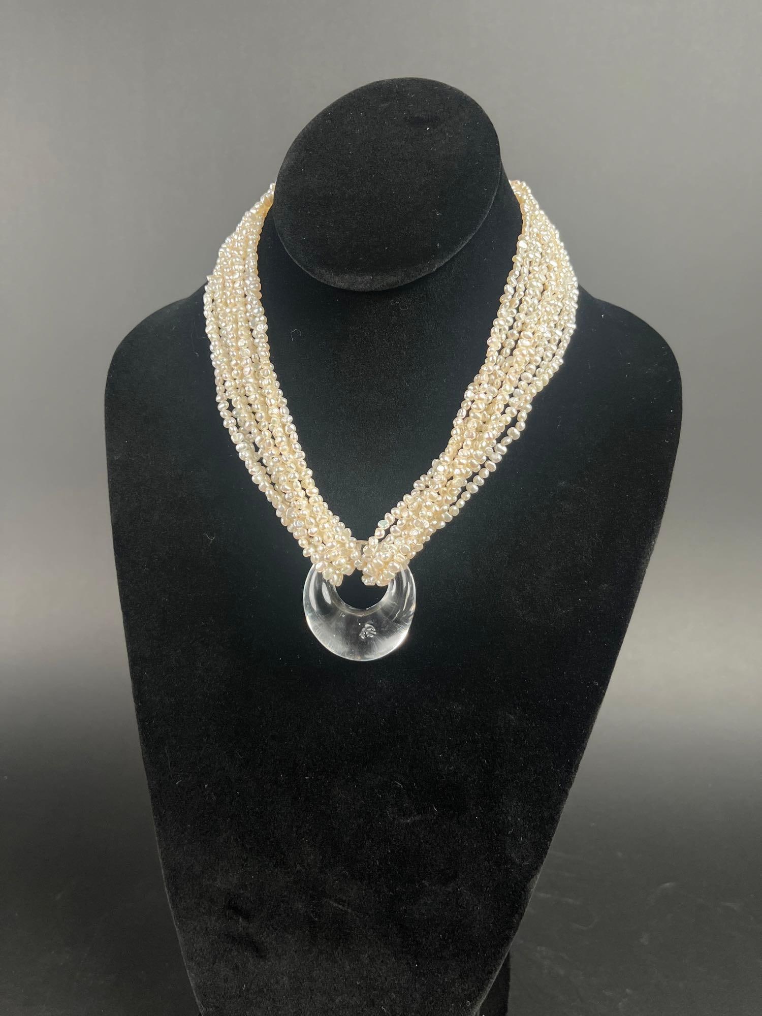 Vintage Carolyn Tanner Multi Pearl and Glass Pendant Necklace: Multi-Strand Freshwater Pearl and Blown Glass Choker by Carolyn Tanner. CIRCA 1980s.10 strand seed bead pearls with a classic infinity knot crystal pendant. 17.5" in length with a trademark stampe
