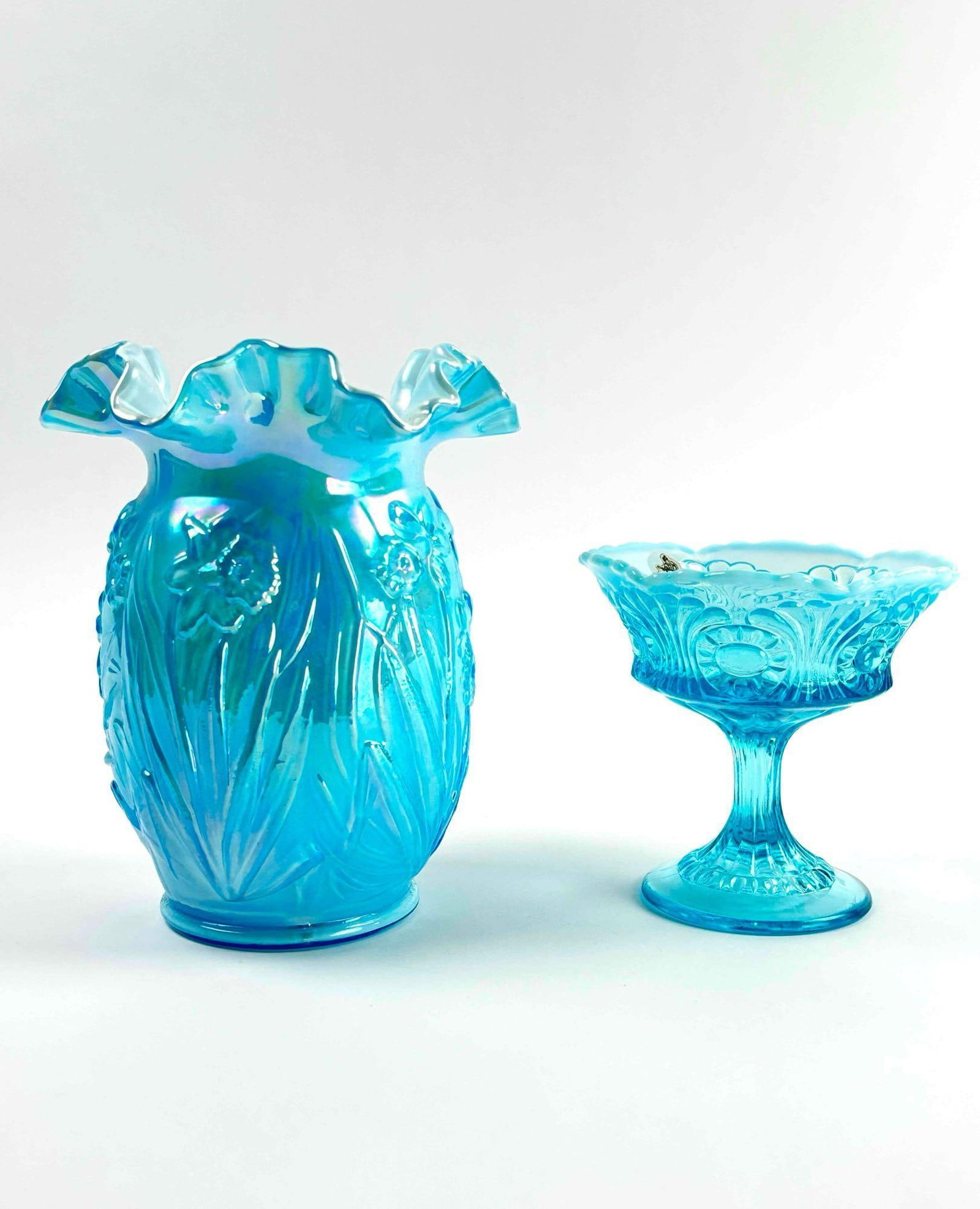 Pair of Fenton Blue Opalescent Glass Pieces: Fenton light blue opalescent daffodil Jonqil Vase and Fenton blue opalescent eye and scroll Compote. Both pieces are in excellent condition. The compote has an original Fenton sticker. Please see phot